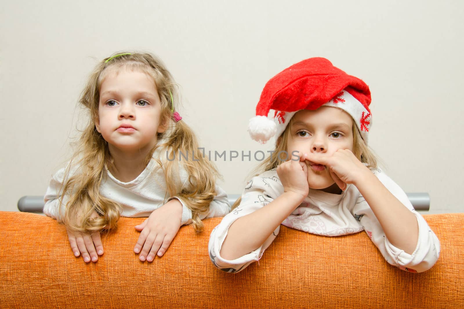 Two girls enthusiastically watching the left leaning back on the couch