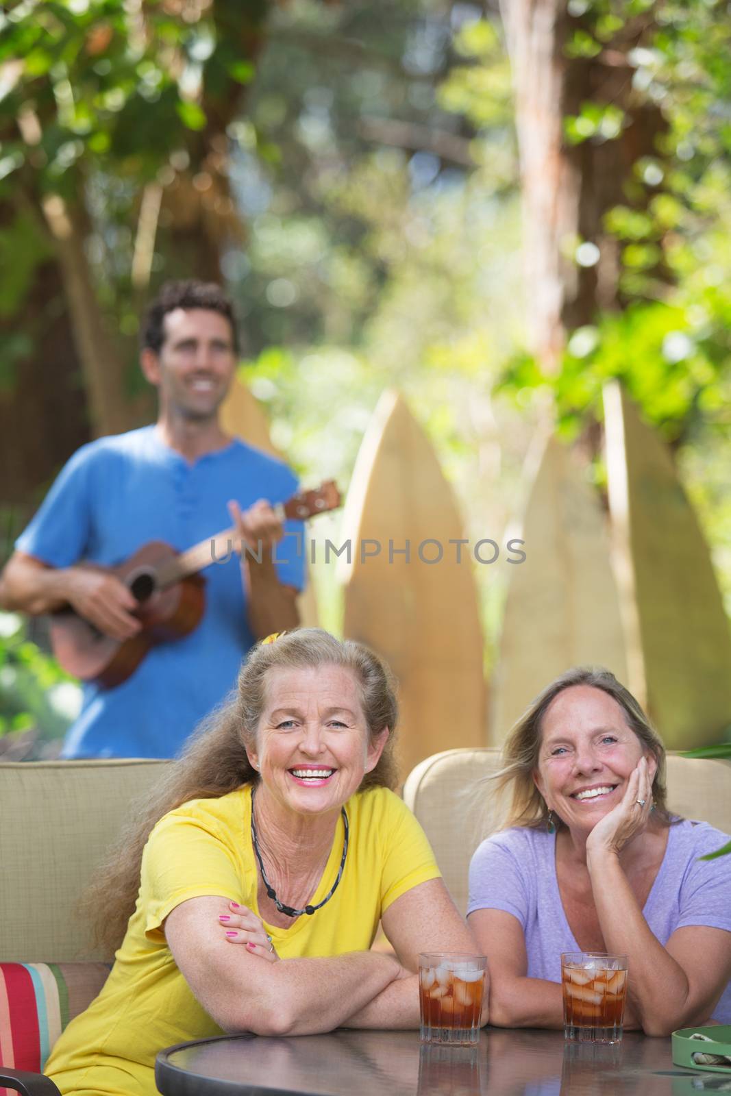 Two smiling female friends near ukulele player in Hawaii