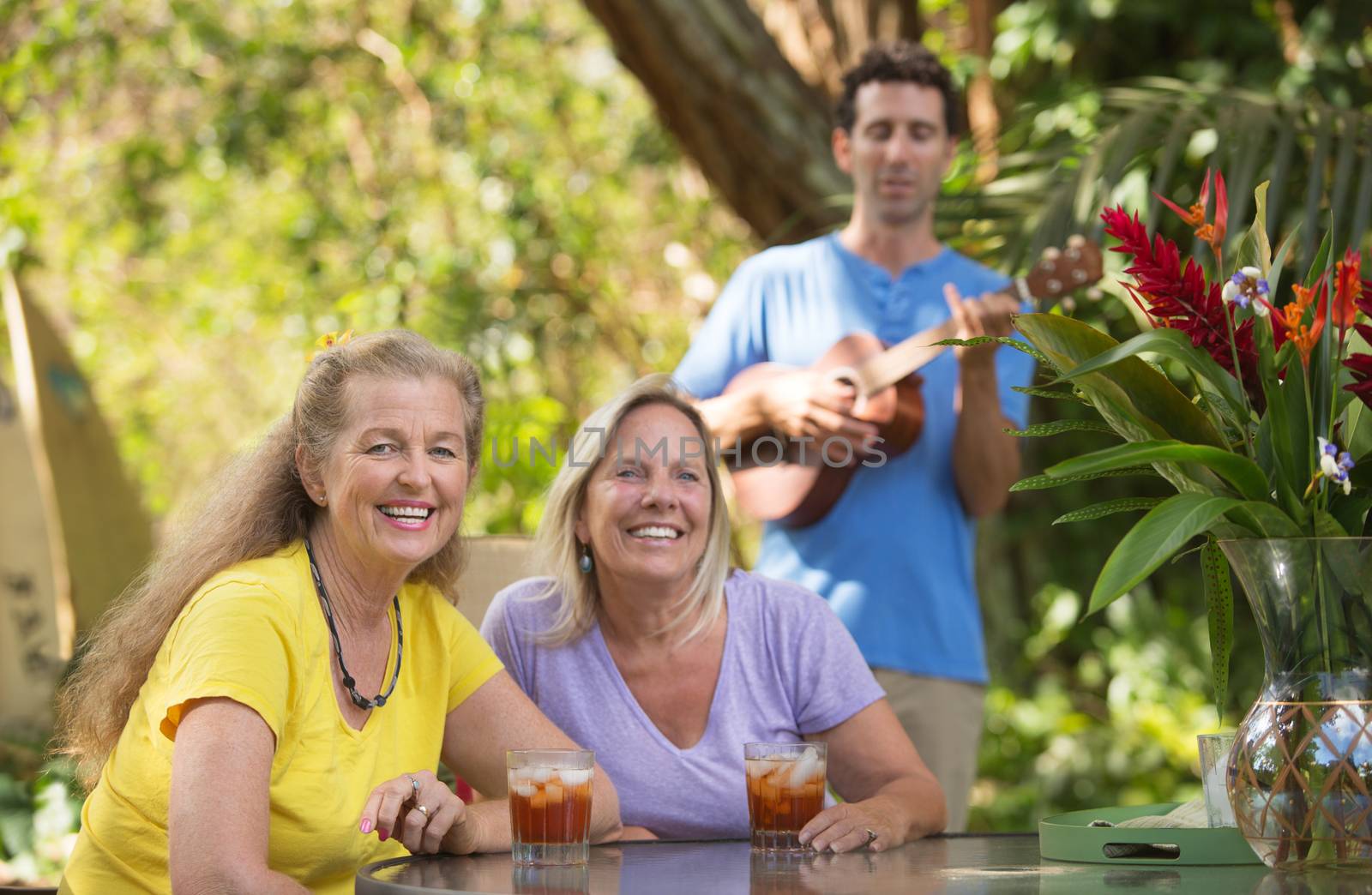 Two beautiful happy women with male ukelele player