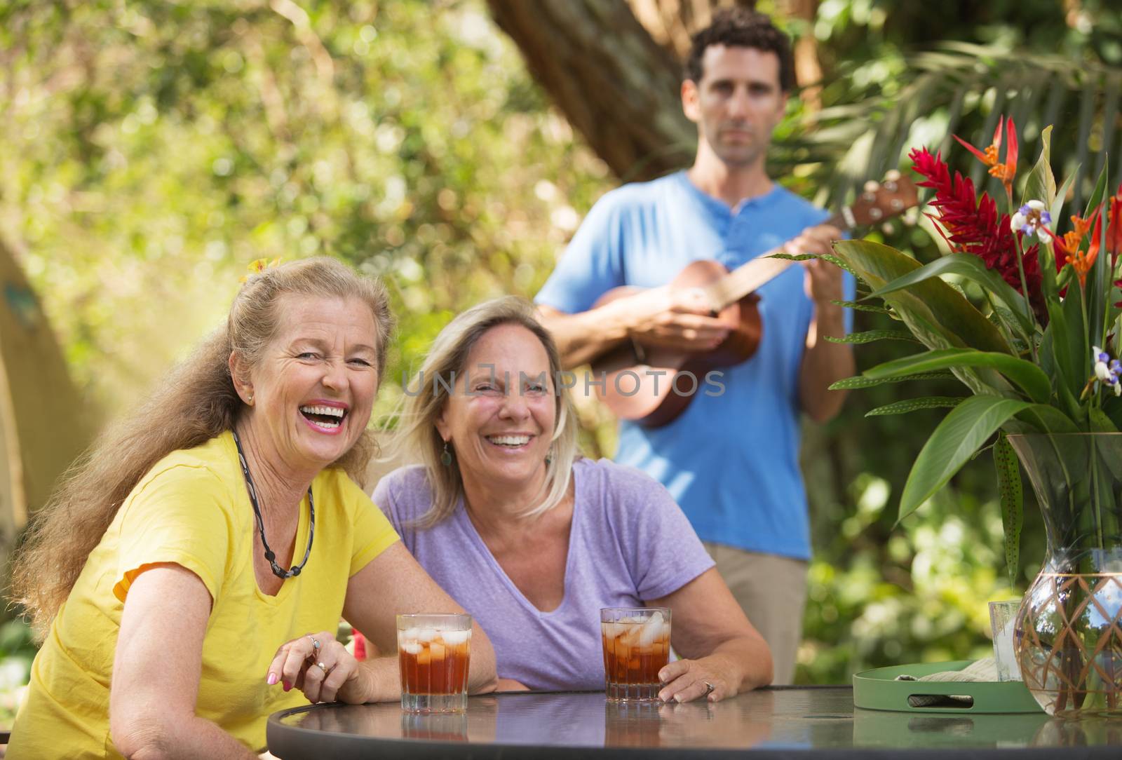 Two laughing women with ukelele player behind them