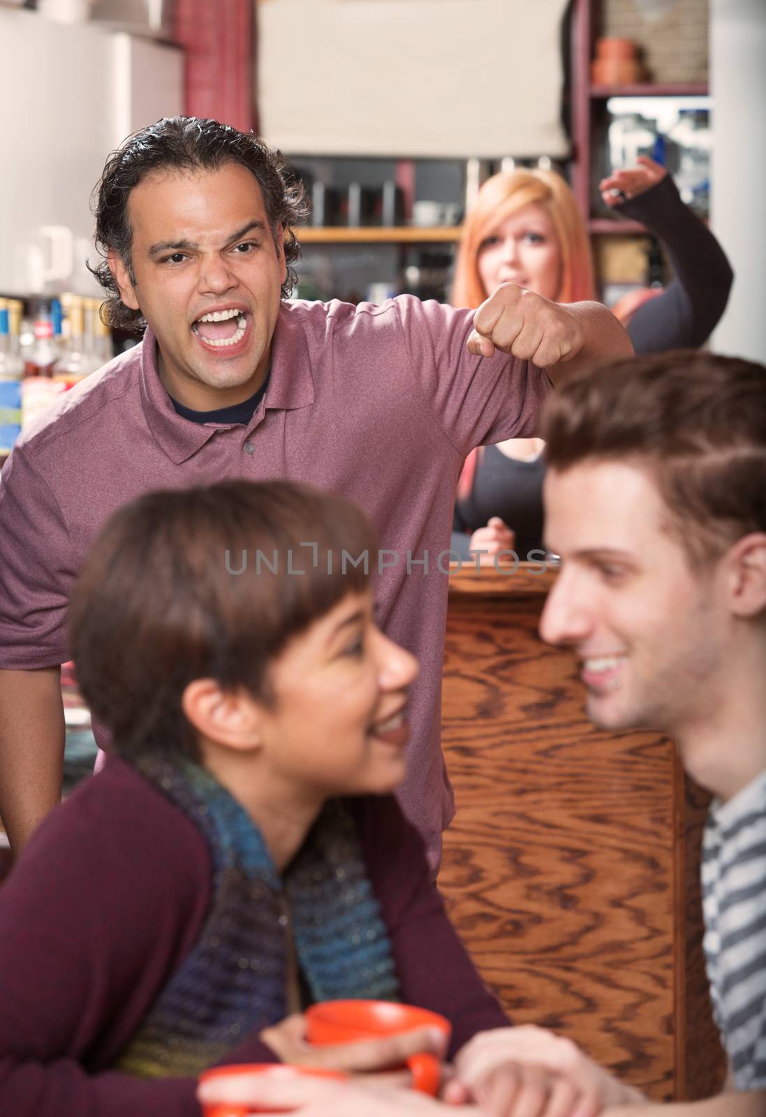 Hostile man with raised fist threatening loving couple in cafe