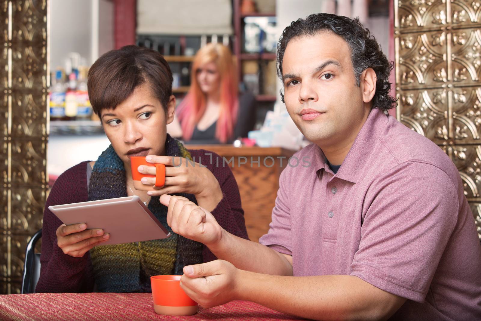 Pretty Hispanic woman reading tablet and ignoring boyfriend