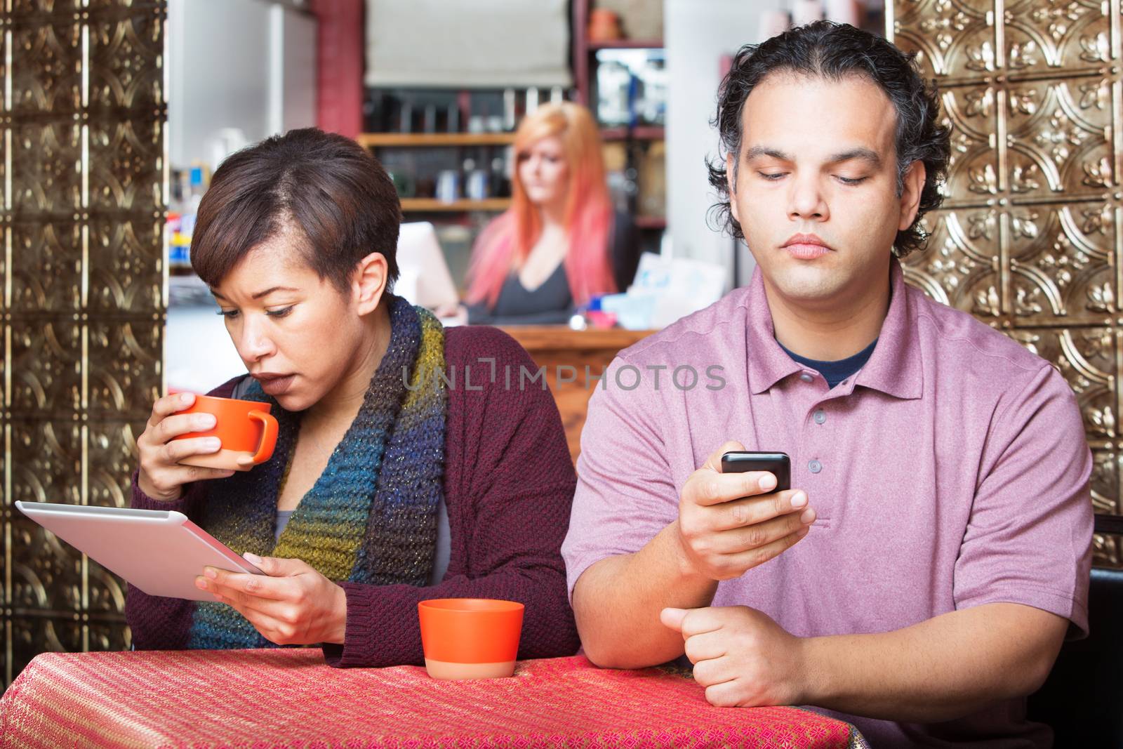 Young distracted African American couple using digital devices in cafe