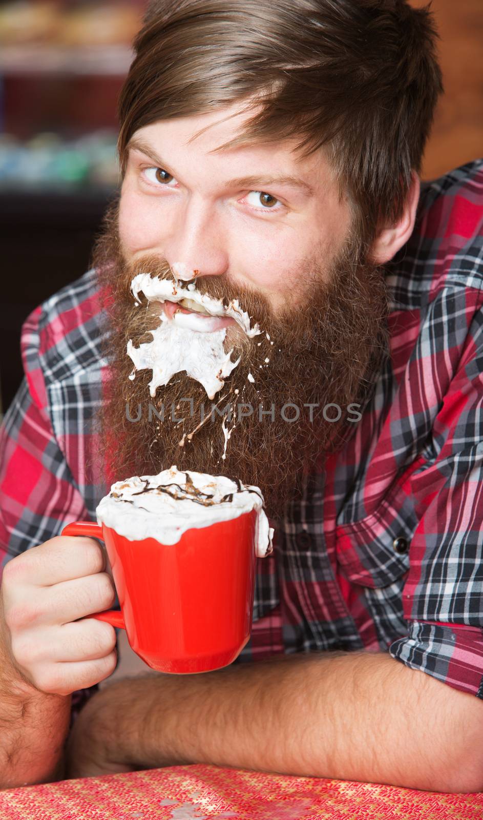 Happy young man with coffee and whipped cream on beard