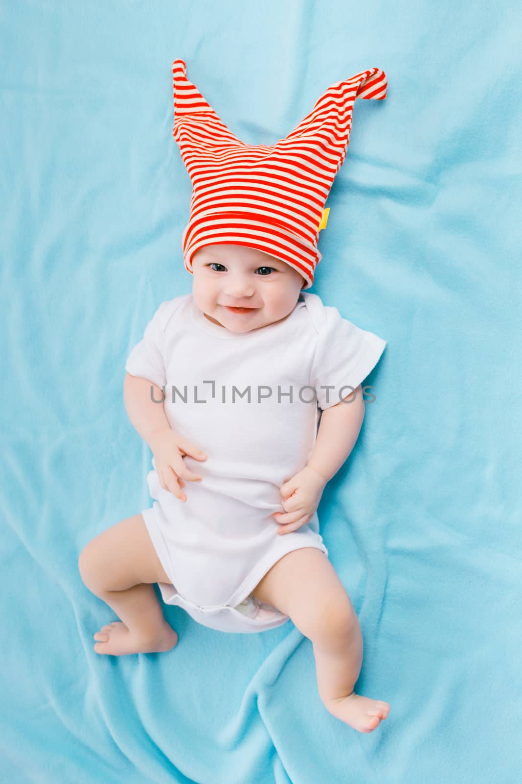 cute toddler in a striped hat on a blue blanket