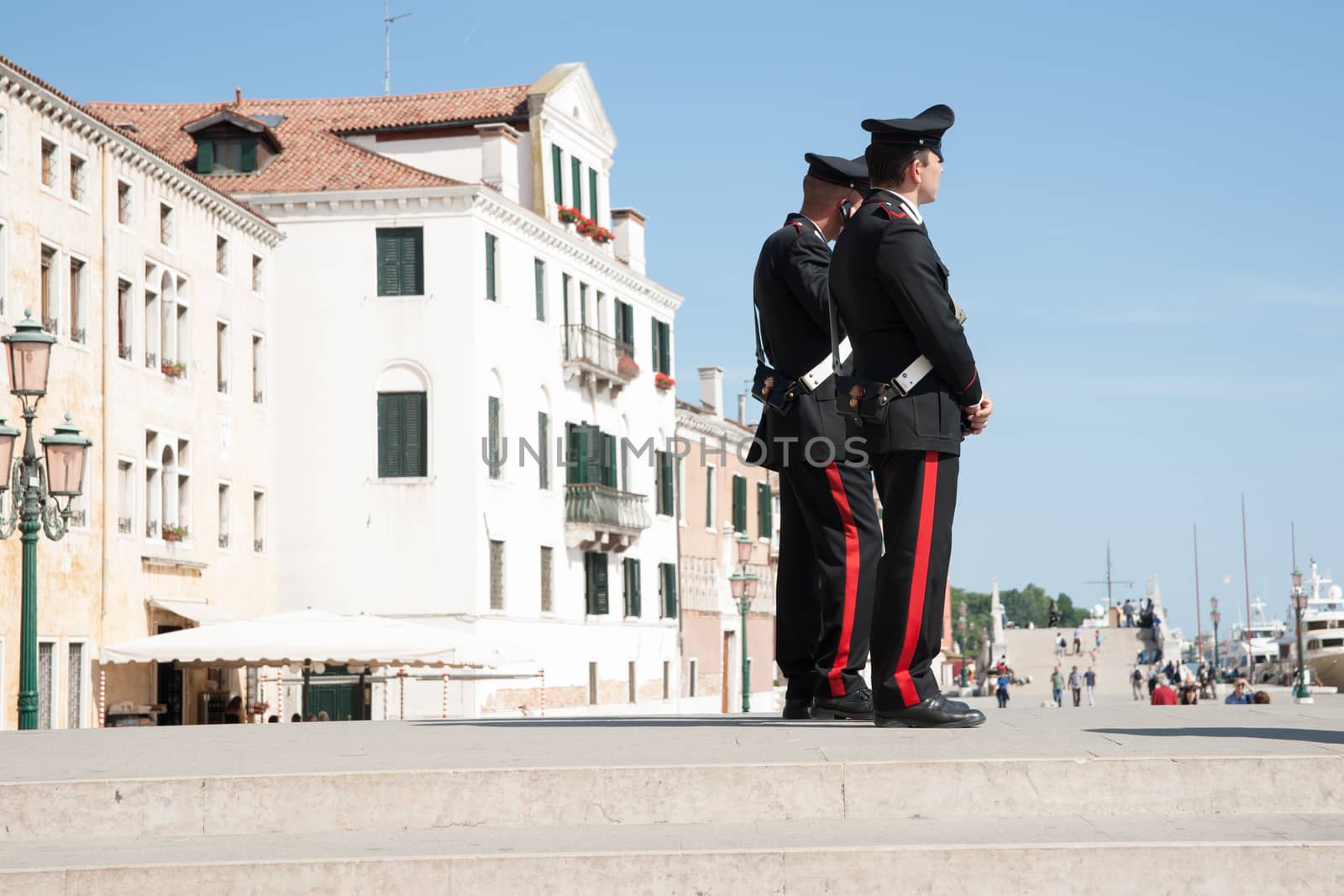 Venice, Italy - May 11, 2011: Two Carabinieri, from one of Italy's two police forces provide travelers with security keeping a watch on activities as tourists pass by near Venice waterfront.