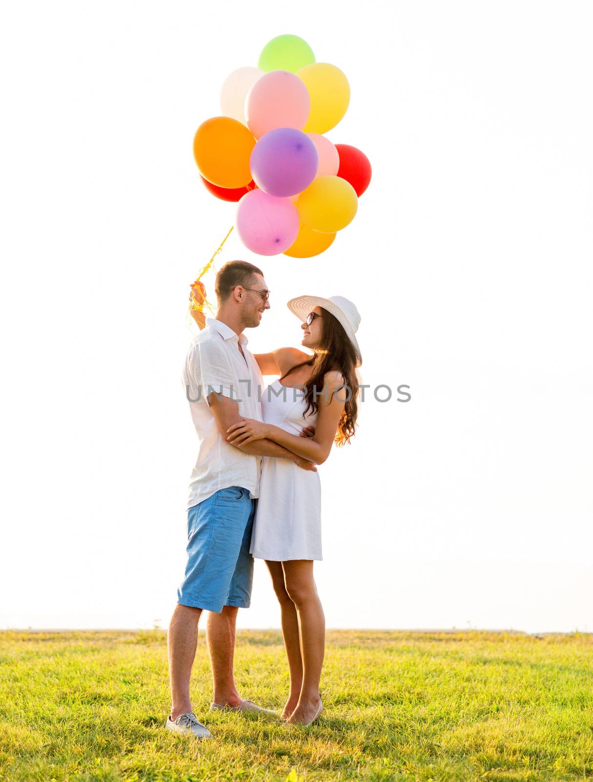 love, wedding, summer, dating and people concept - smiling couple wearing sunglasses with balloons hugging outdoors