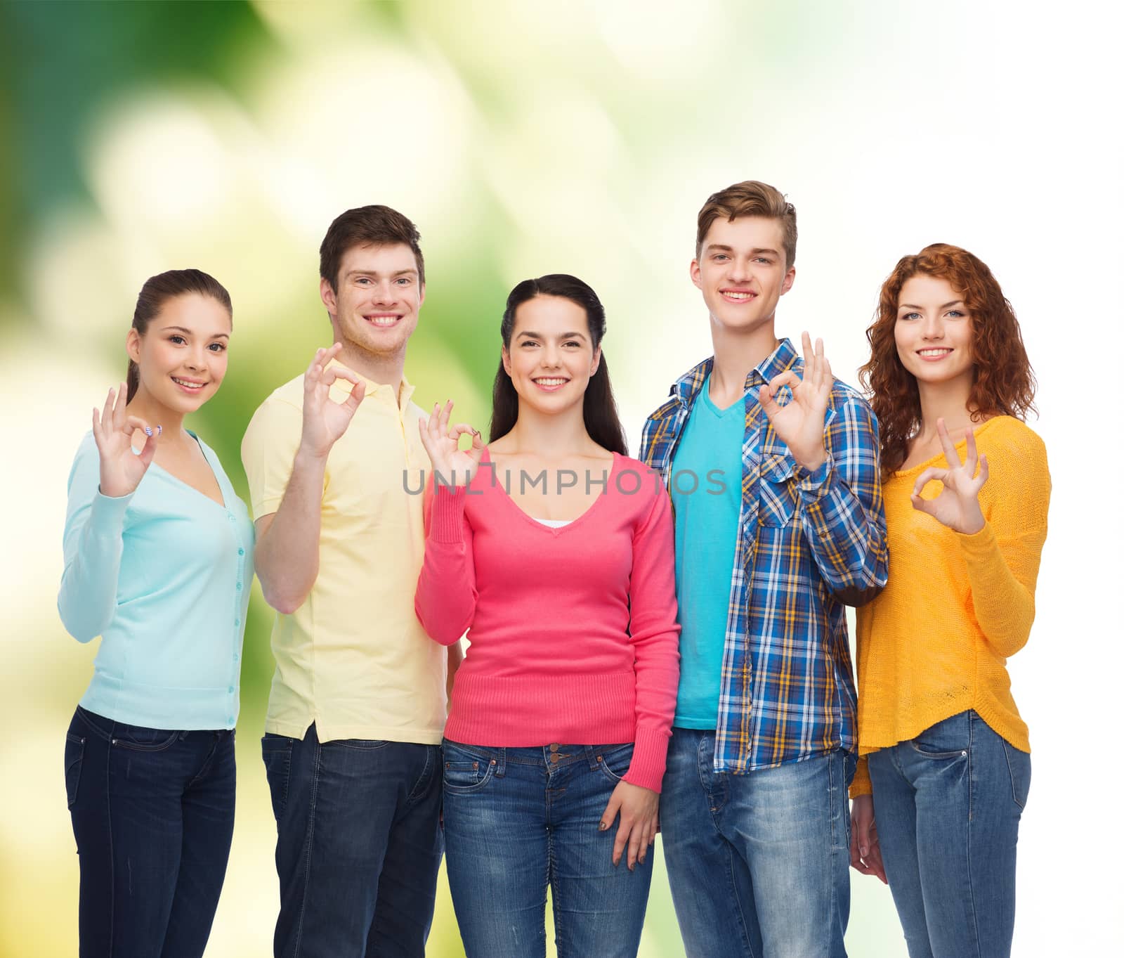 group of smiling teenagers over green background by dolgachov