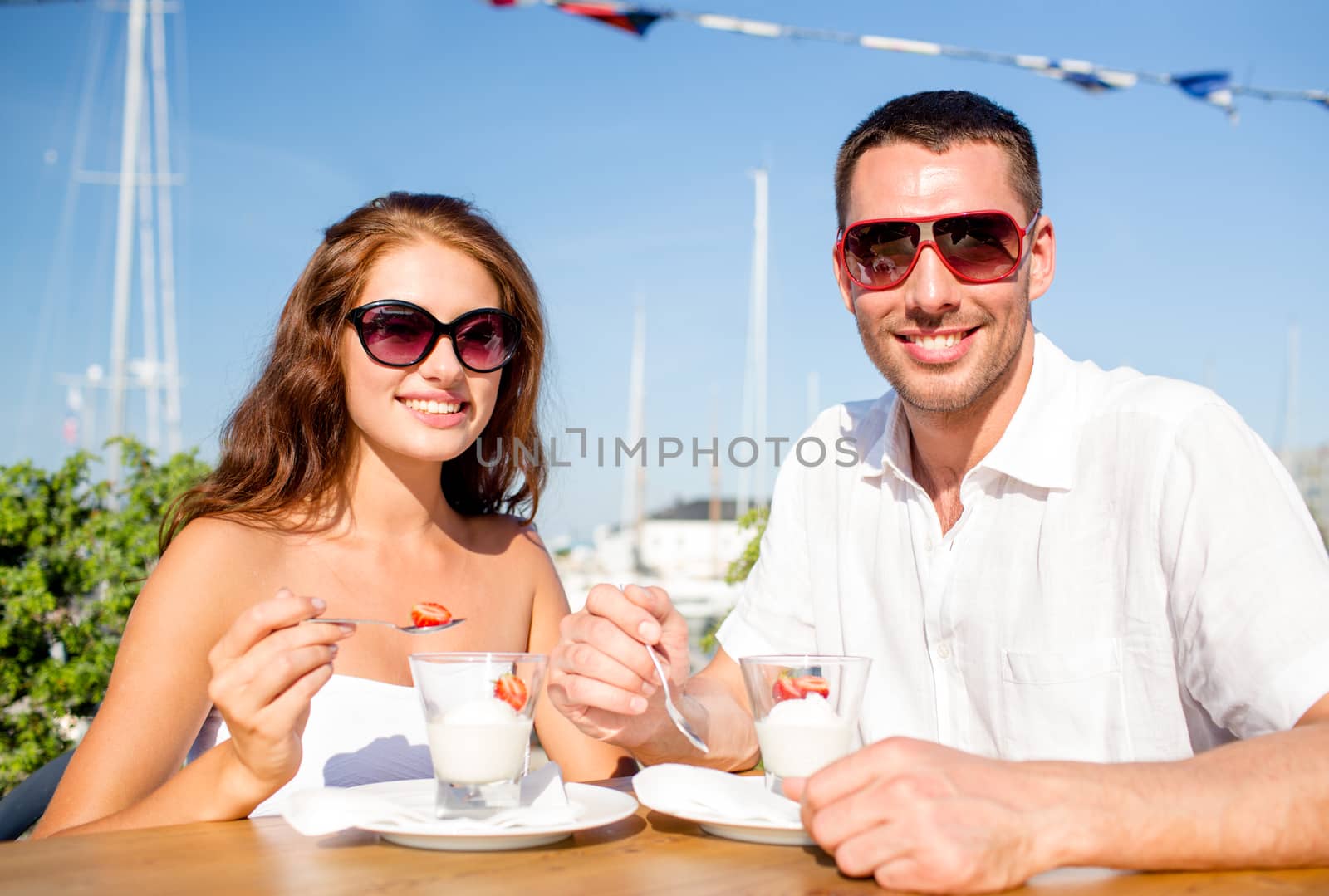 love, dating, people and food concept - smiling couple wearing sunglasses eating dessert at cafe