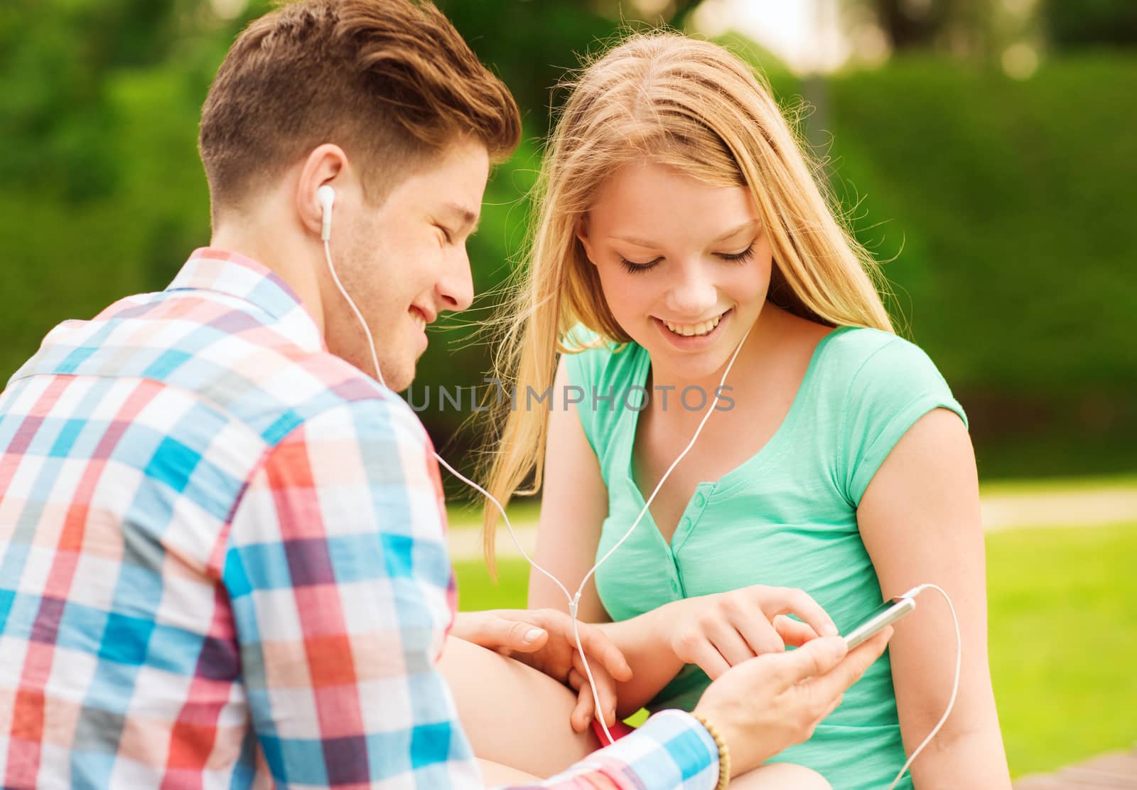 smiling couple with smartphone and earphones by dolgachov