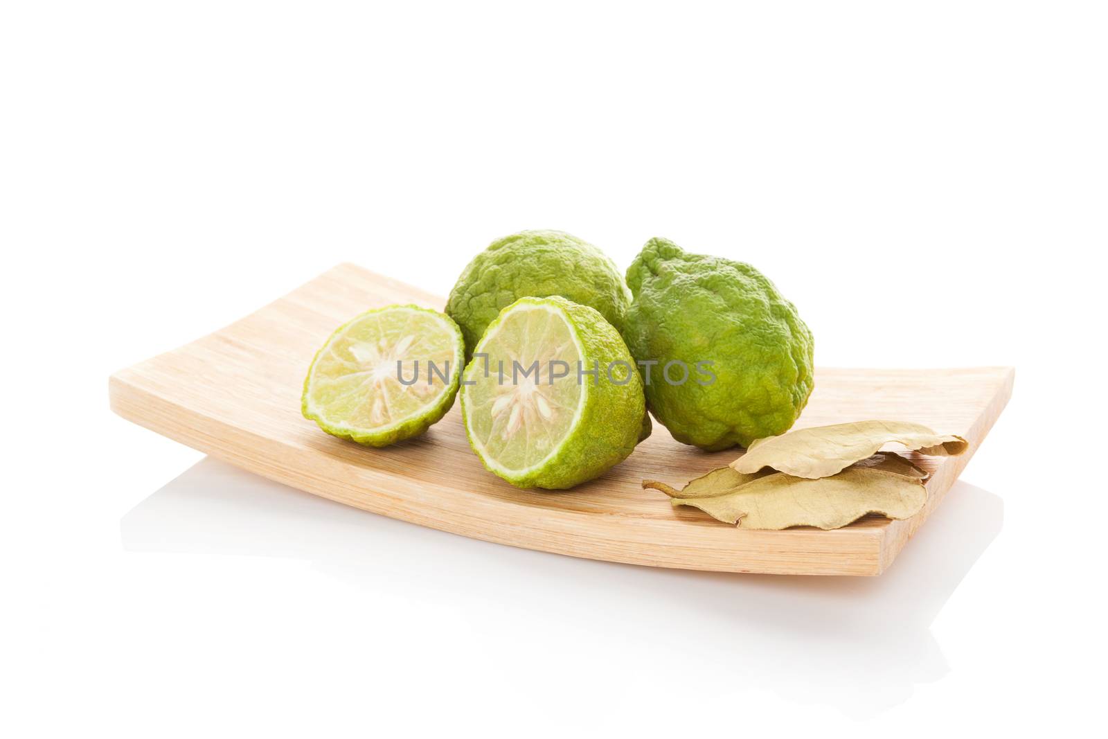 Bergamot oranges and dry leaves on wooden plate isolated on white background. Culinary asian tropical fruit eating.