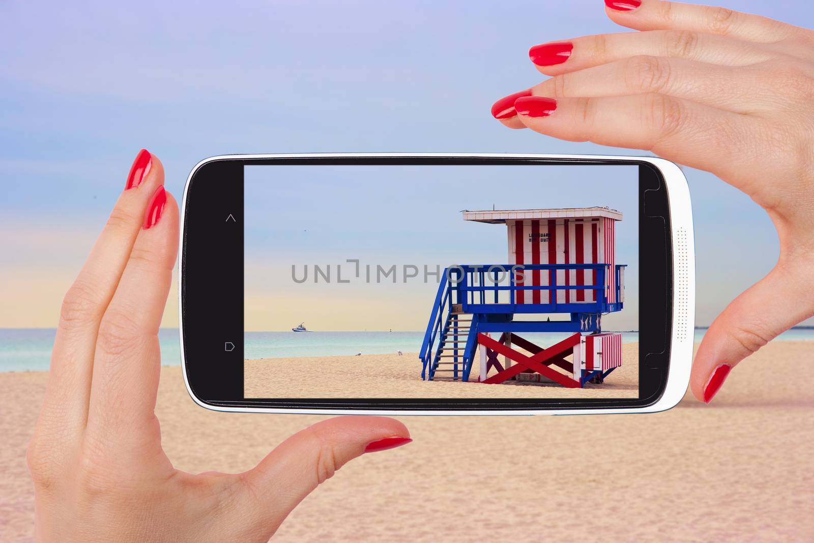 Female tourist taking snapshot with smartphone of lifeguard cabin, Miami Beach, Florida, USA. Backpacking, vagabonding, travelling.
