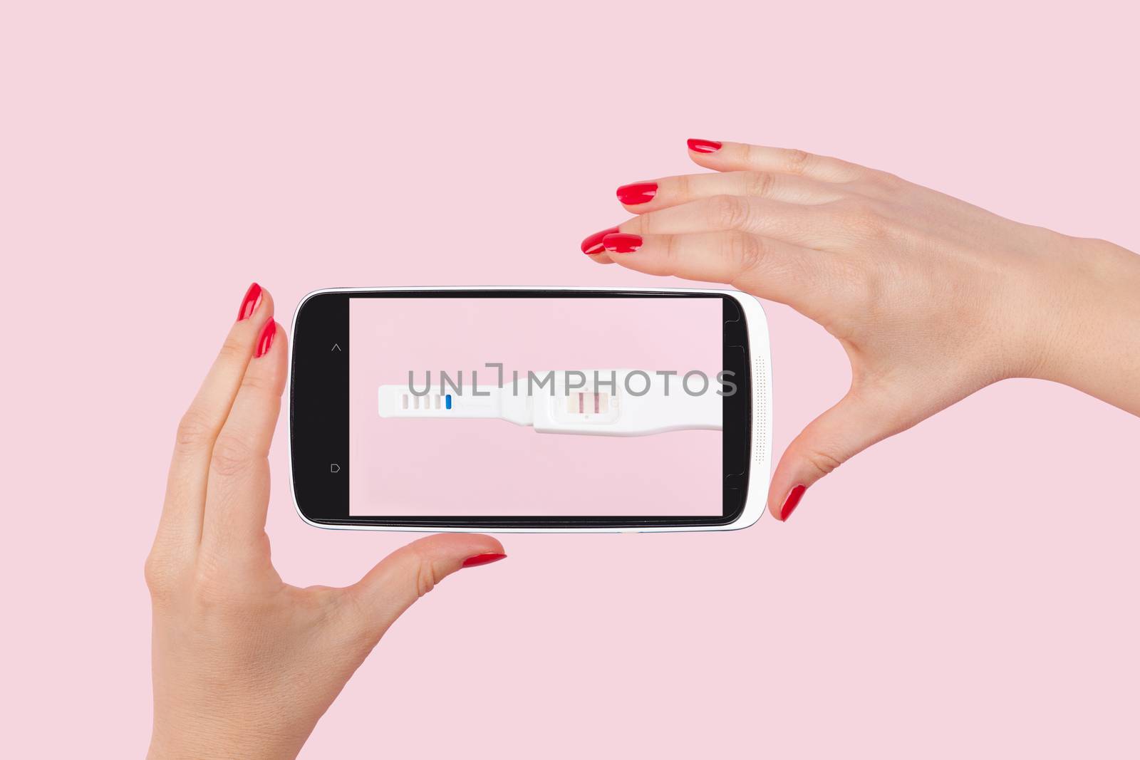 Beautiful female hand with red fingernails holding smartphone with positive pregnancy test isolated on pink background. Motherhood, pregnancy, birth control concept. The future of medicine, high tech.