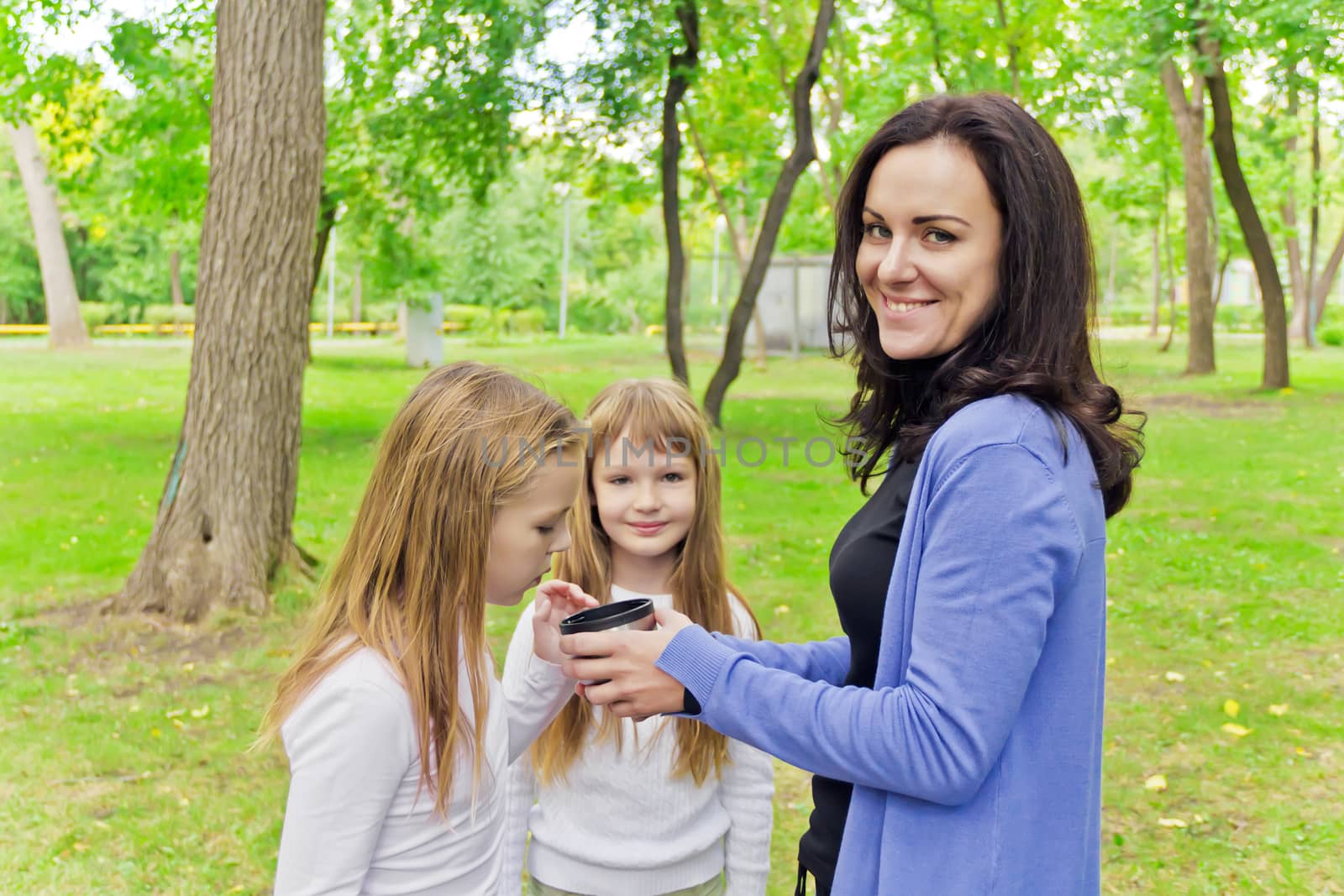 Photo of woman with two girls drinking tea