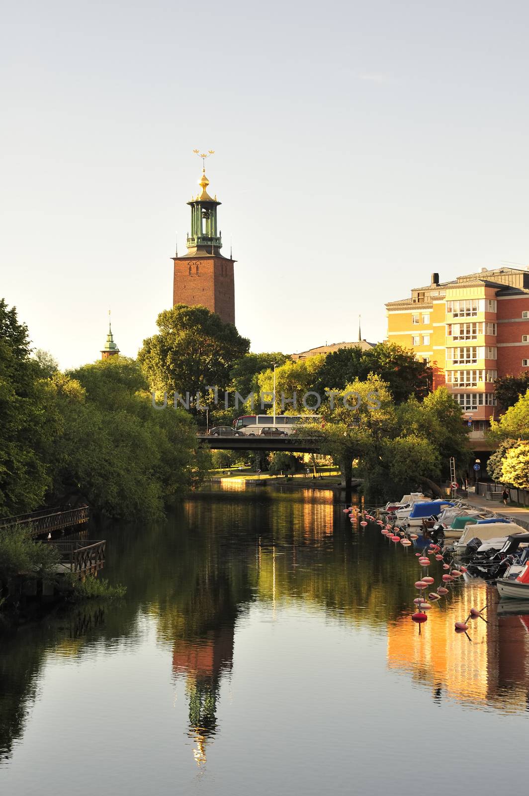 The Stockholm Stadshuset in early morning light perfectly reflected in still water.