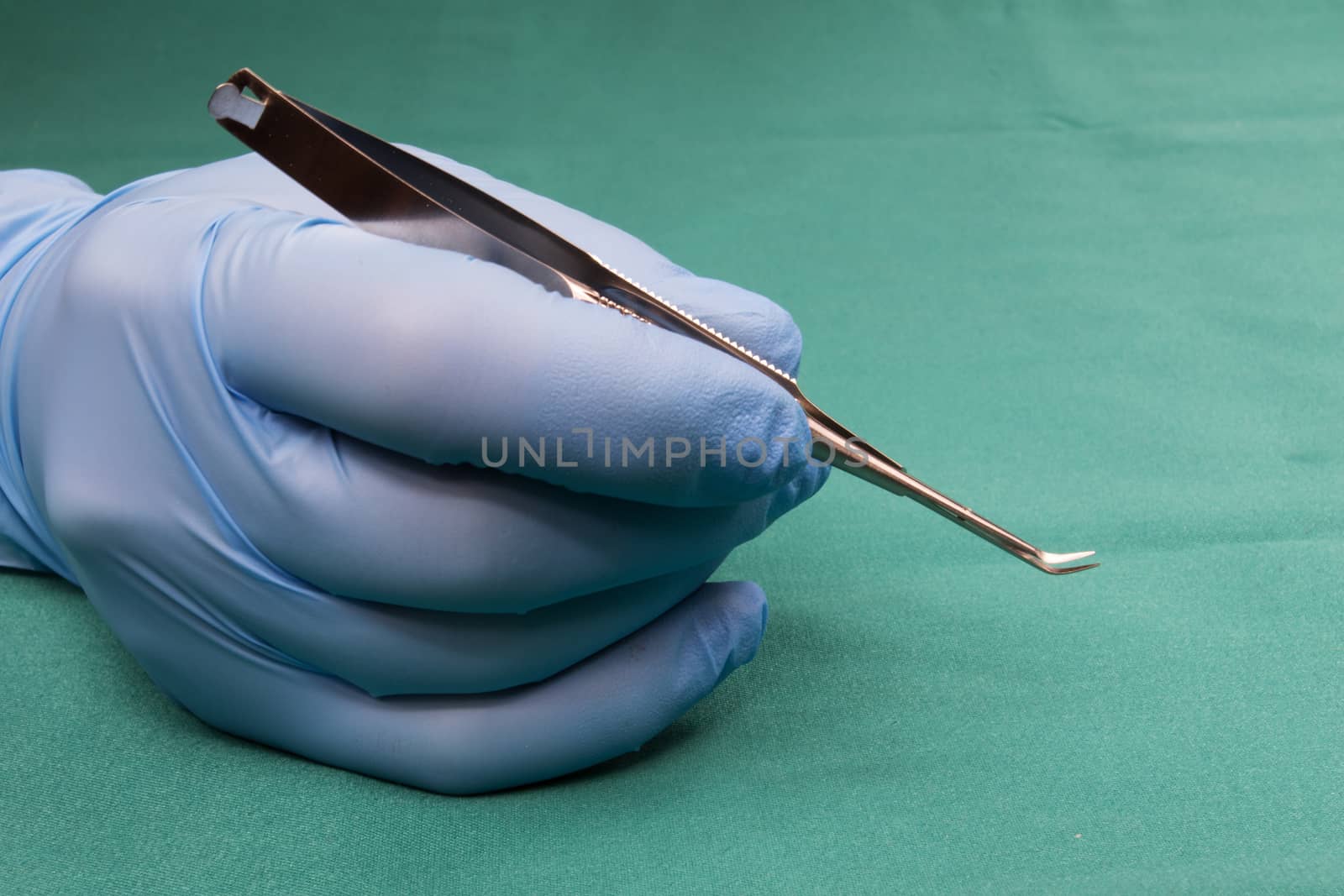 Surgeon holding micro surgical tool.Sargeon hand  in blue glove.Surgeon holding Scissors,soft curve..The background is blue tablecloth operating