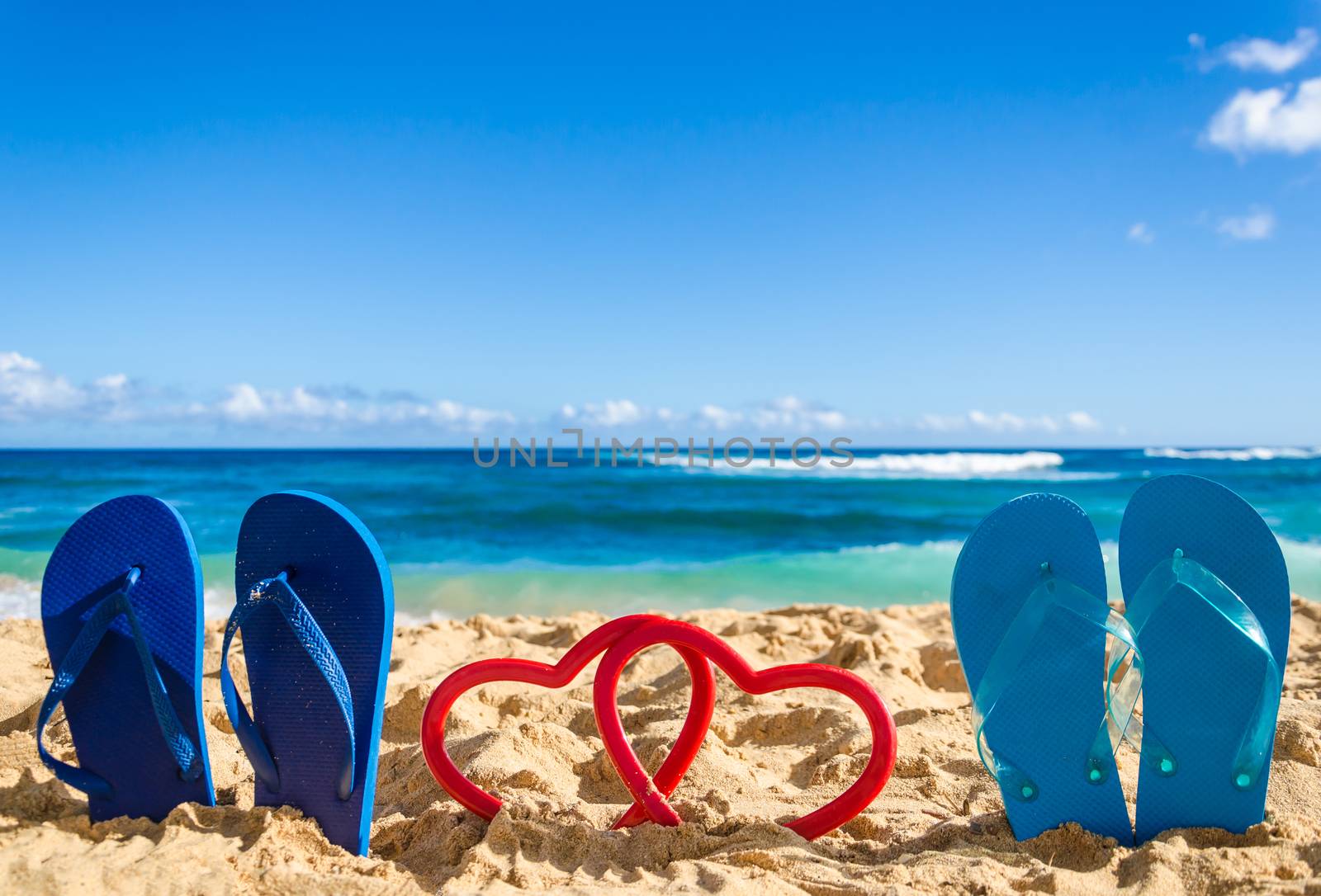 Flip flops with heart shapes on the sandy beach by EllenSmile