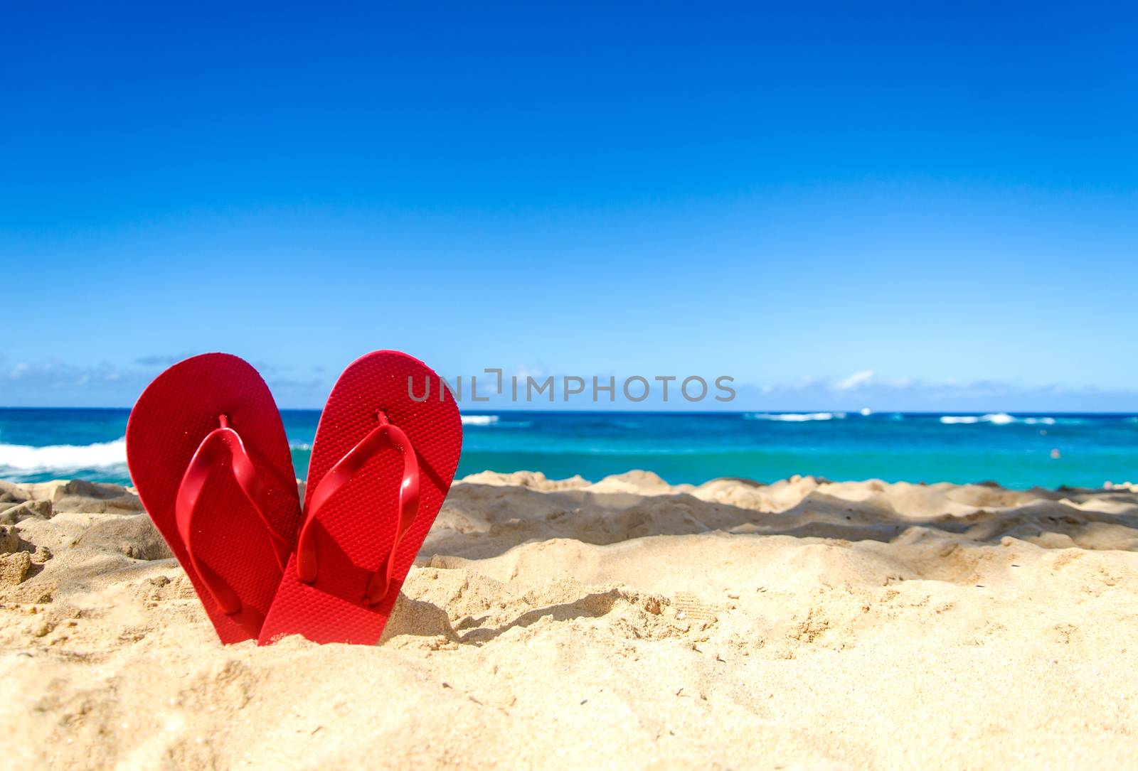 Red flip flops in heart shapes on the sandy beach in Hawaii, Kauai (romantic concept) 