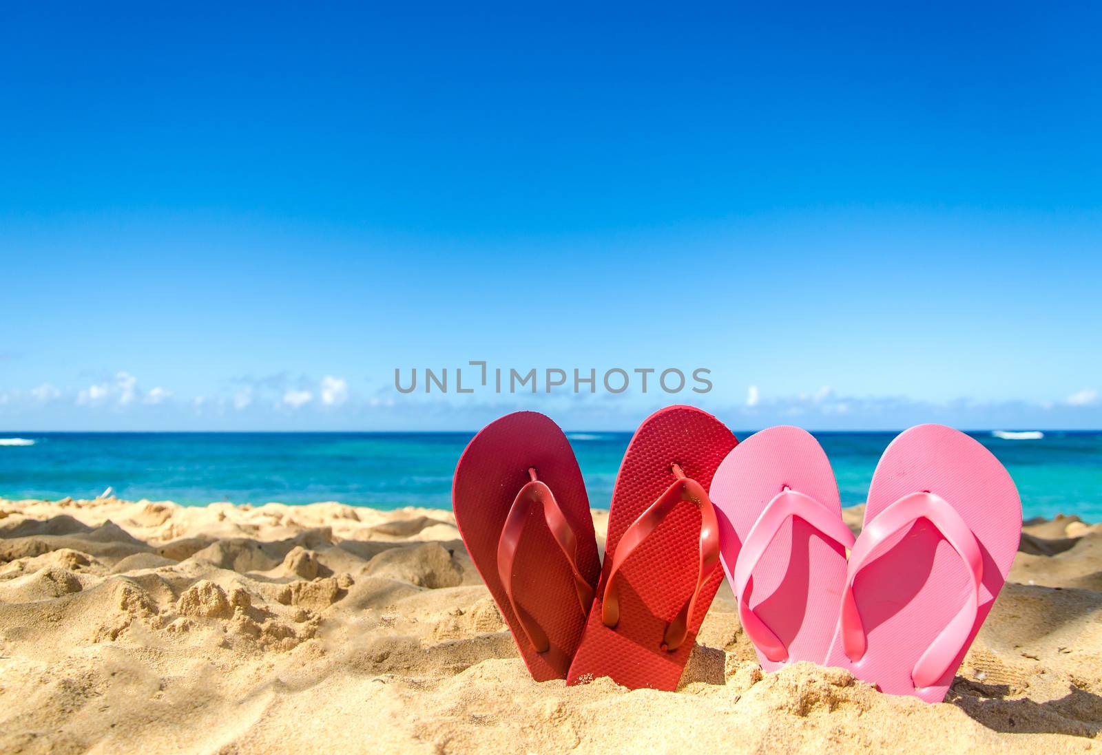 Red and pink flip flops on the sandy beach by EllenSmile
