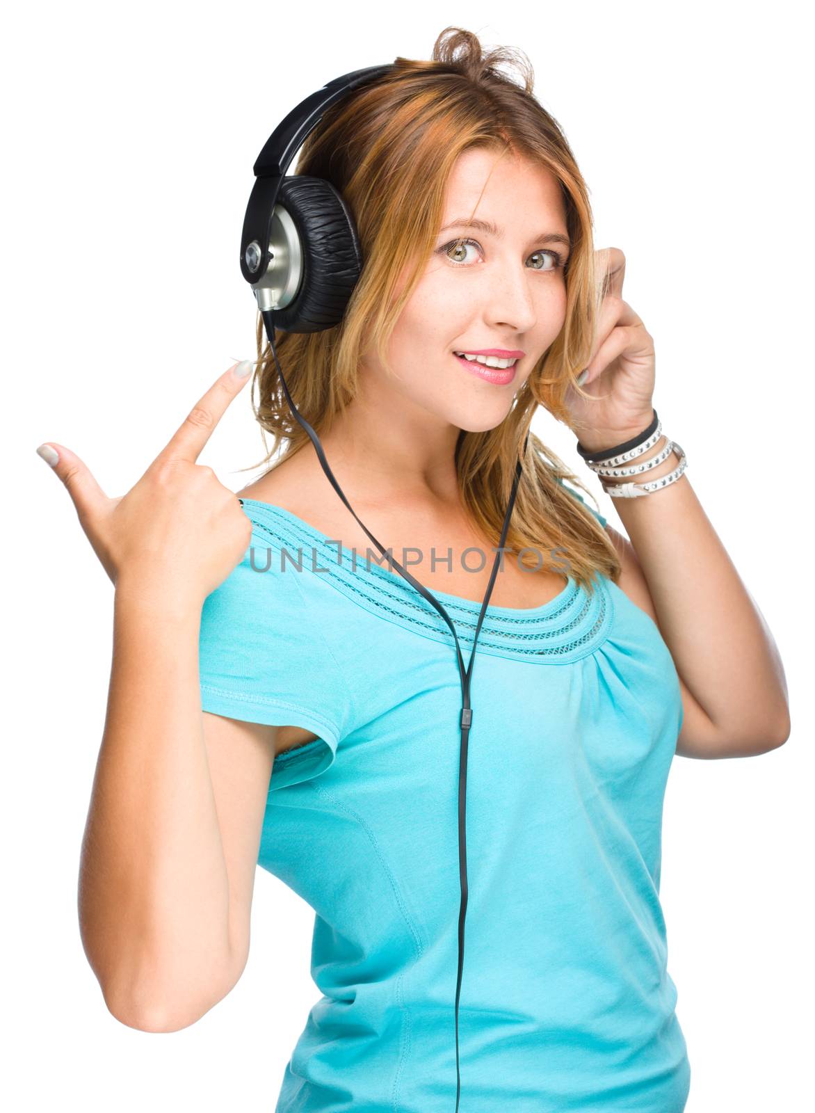 music and technology concept - young woman listening to music and show on her headphones, isolated on white background
