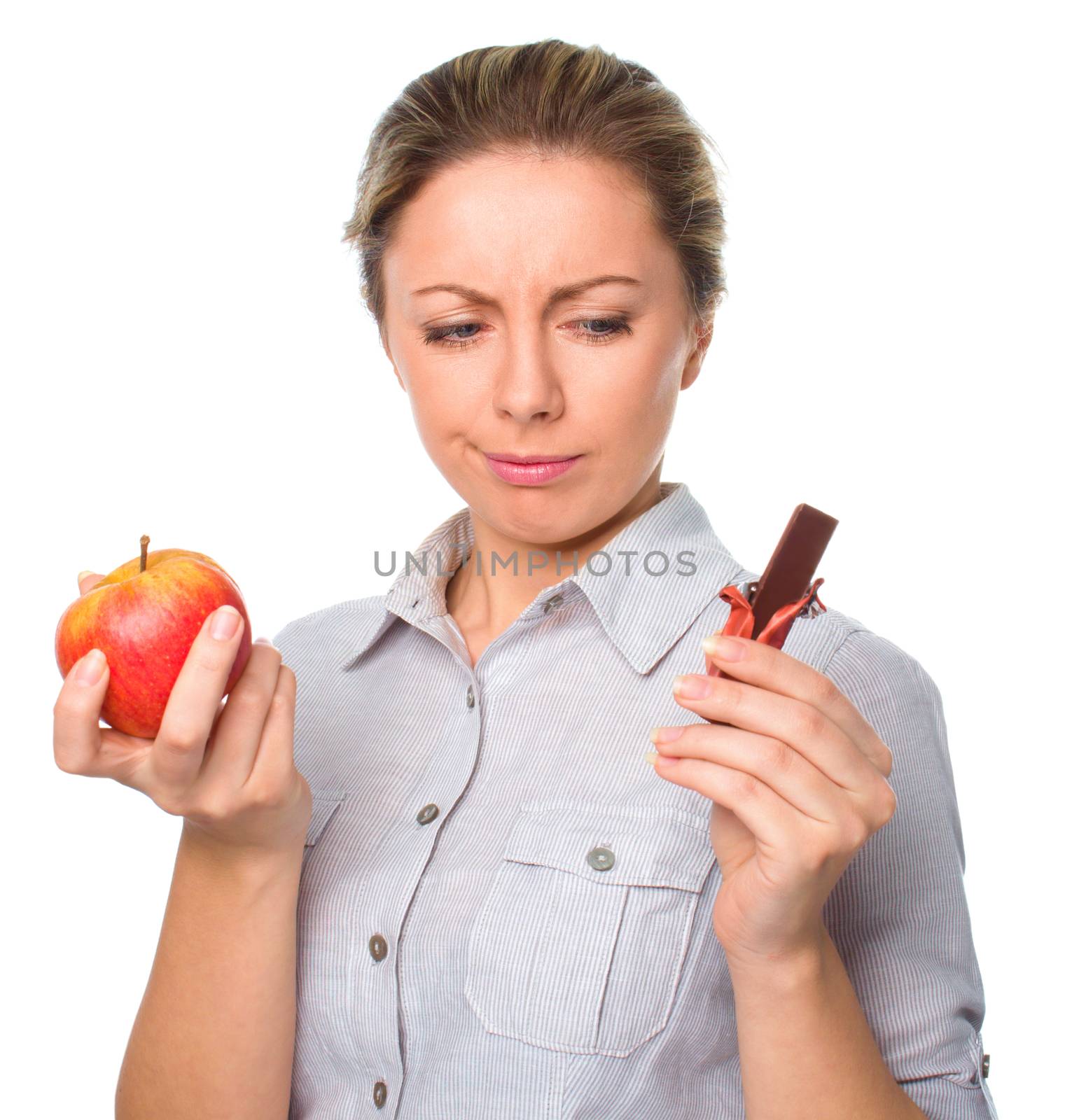 Diet concept: Woman choosing between fruits and chocolate isolated over white