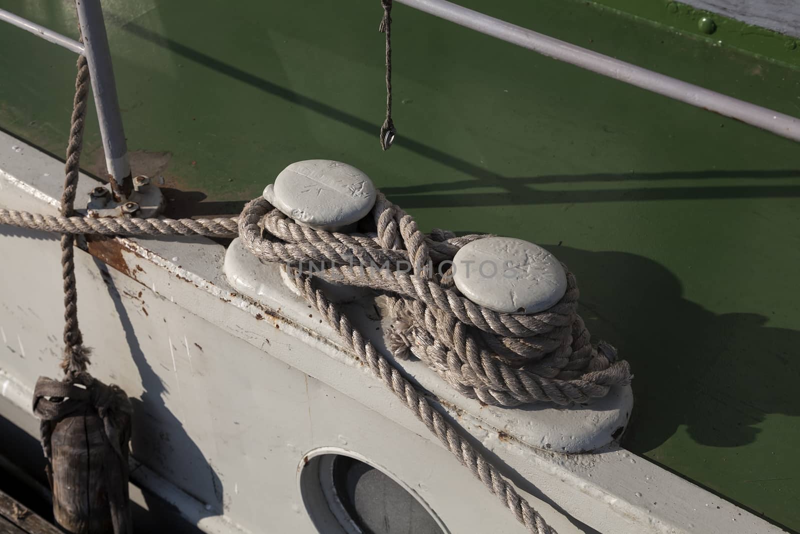 A fender on a boat and some rope to keep it safe in harbor