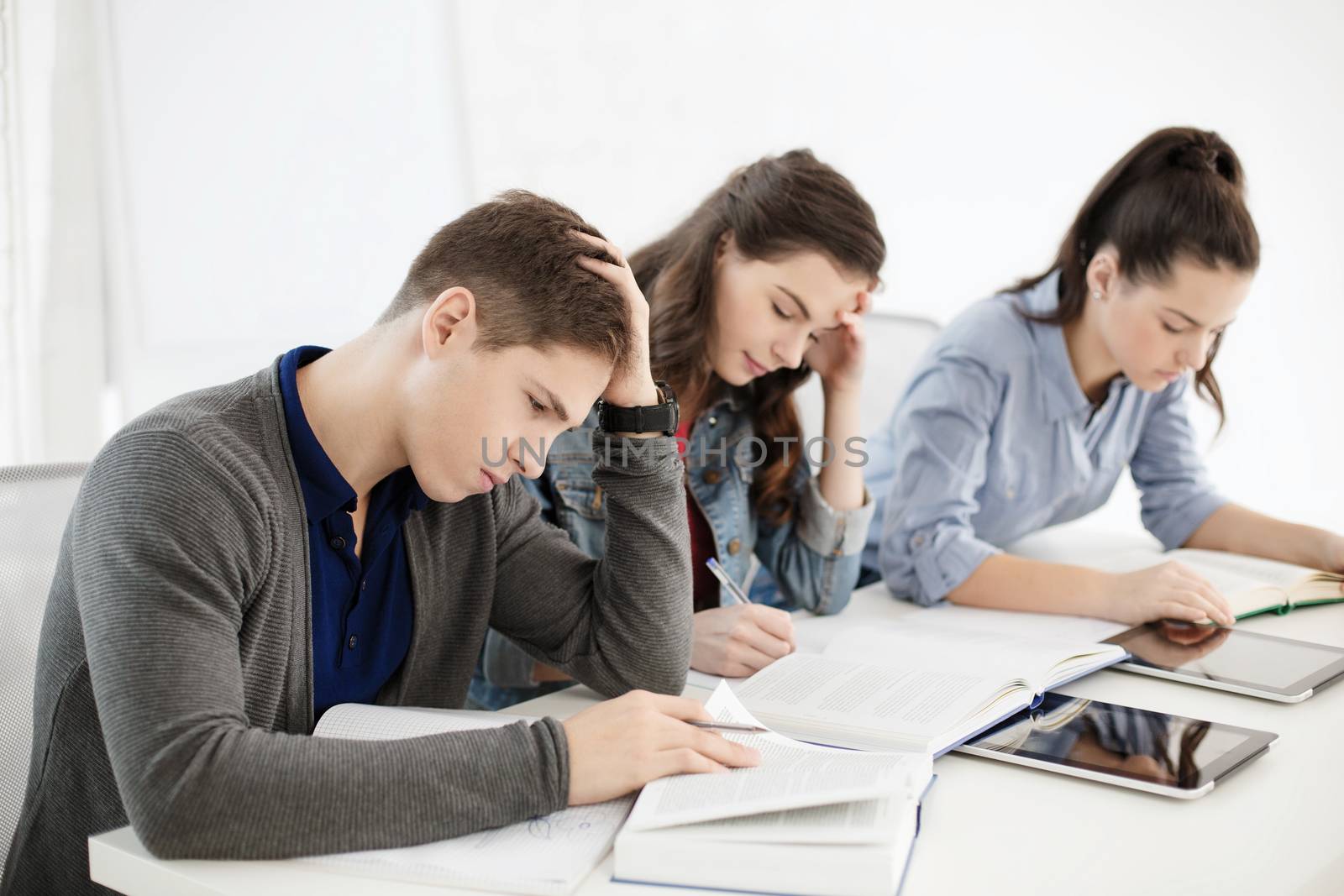 school and education concept - group of tired students with notebooks at school