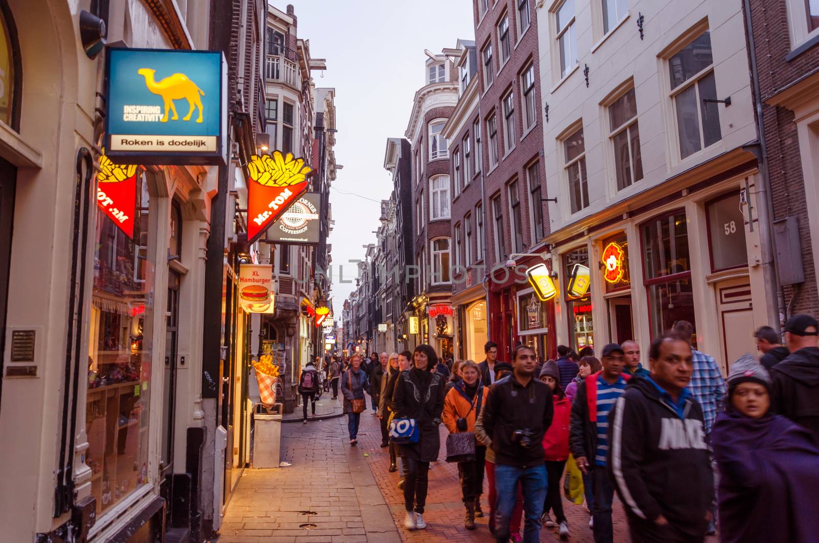 Amsterdam, Netherlands - May 8, 2015: People visit red-light district on May 8, 2015 in Amsterdam. This district consists of a network of alleys containing approximately three hundred one-room cabins rented by prostitutes