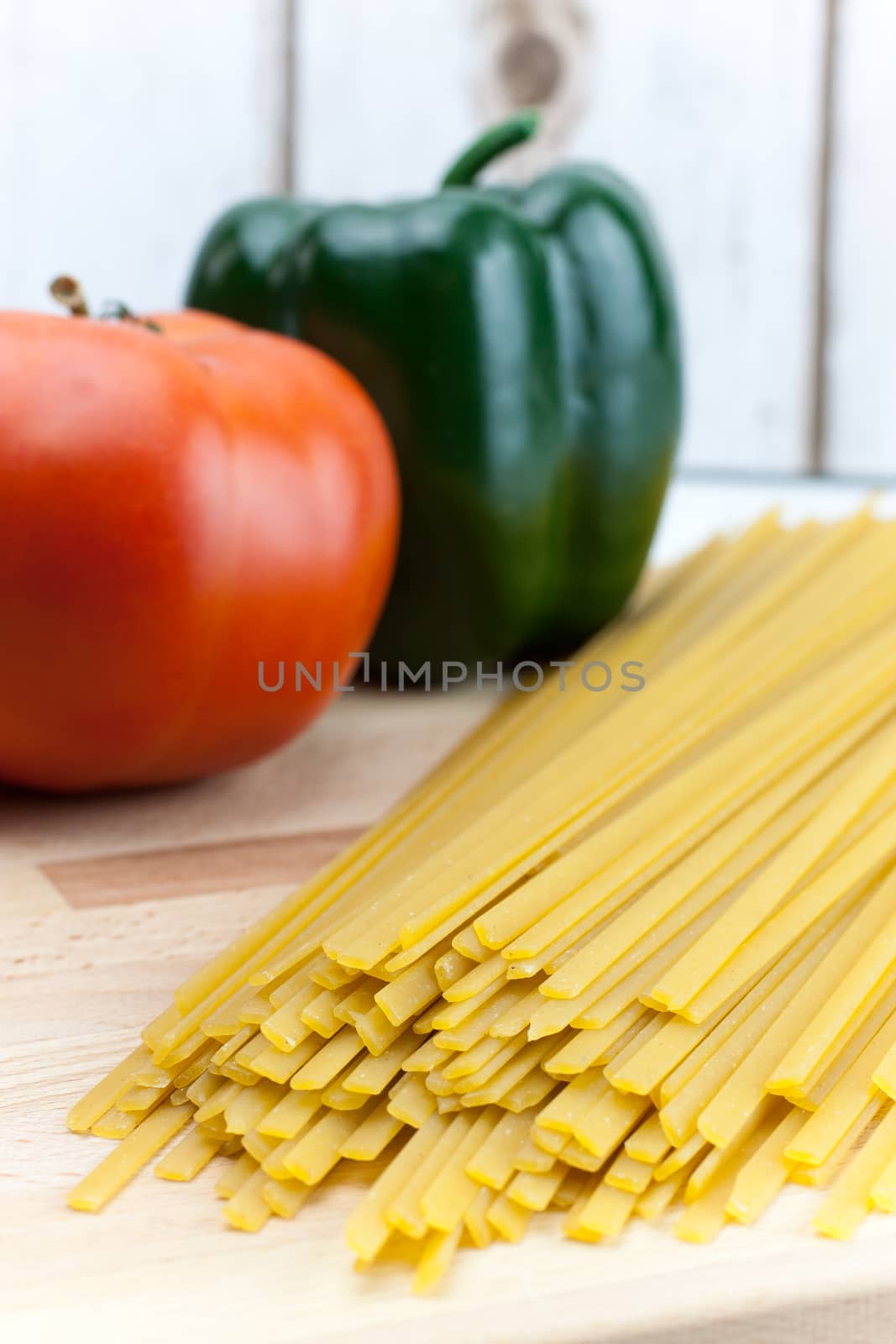 Fetticcine pasta with vegetables on a counter top in preperation to a meal.
