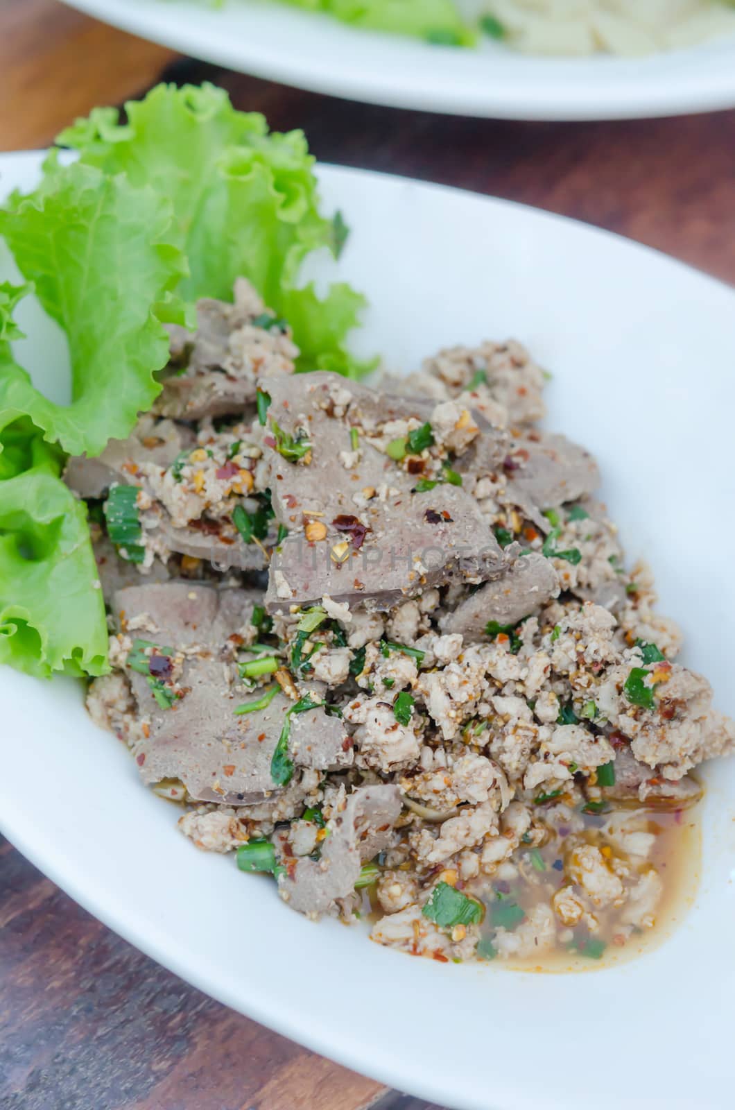 spicy minced pork eaten with fresh vegetable on plate