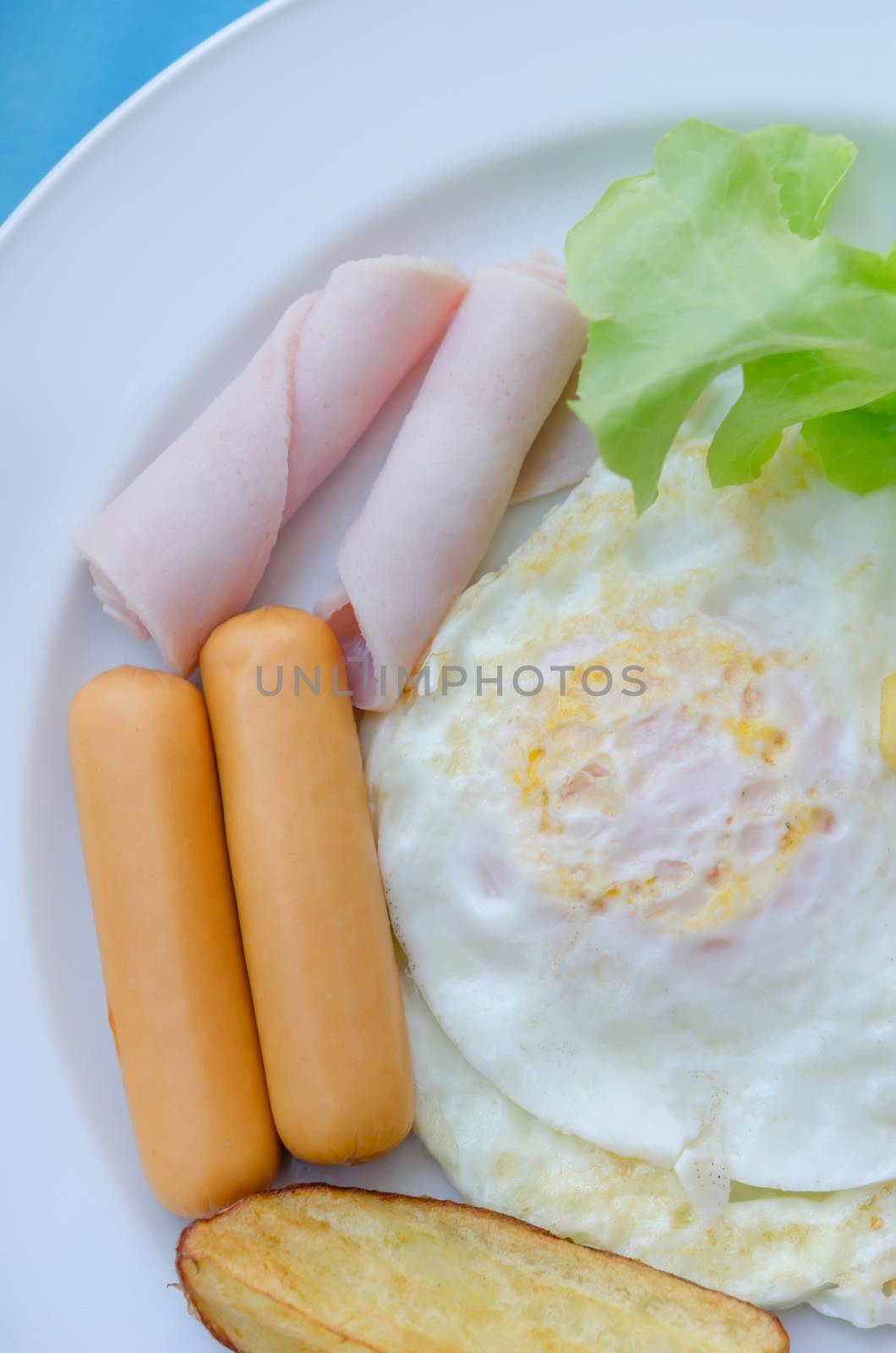 fried egg , ham , sausage and grilled potato on dish , fresh breakfast