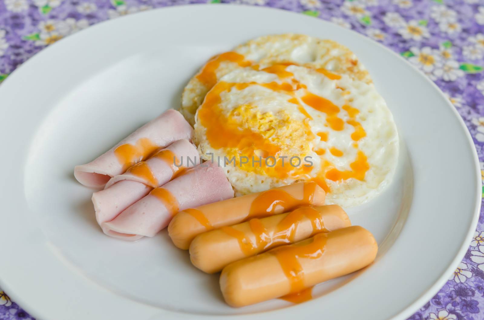 fried egg , ham , sausage with sauce on  dish