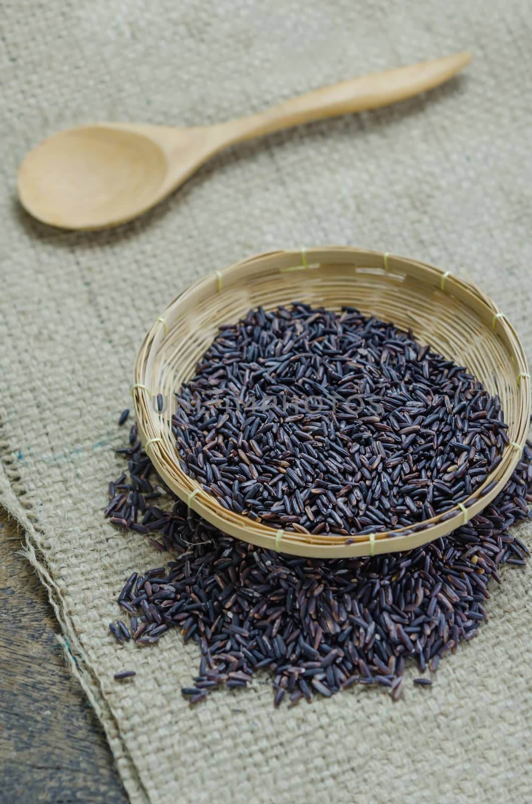 raw purple Riceberry rice in bamboo basket with wooden spoon