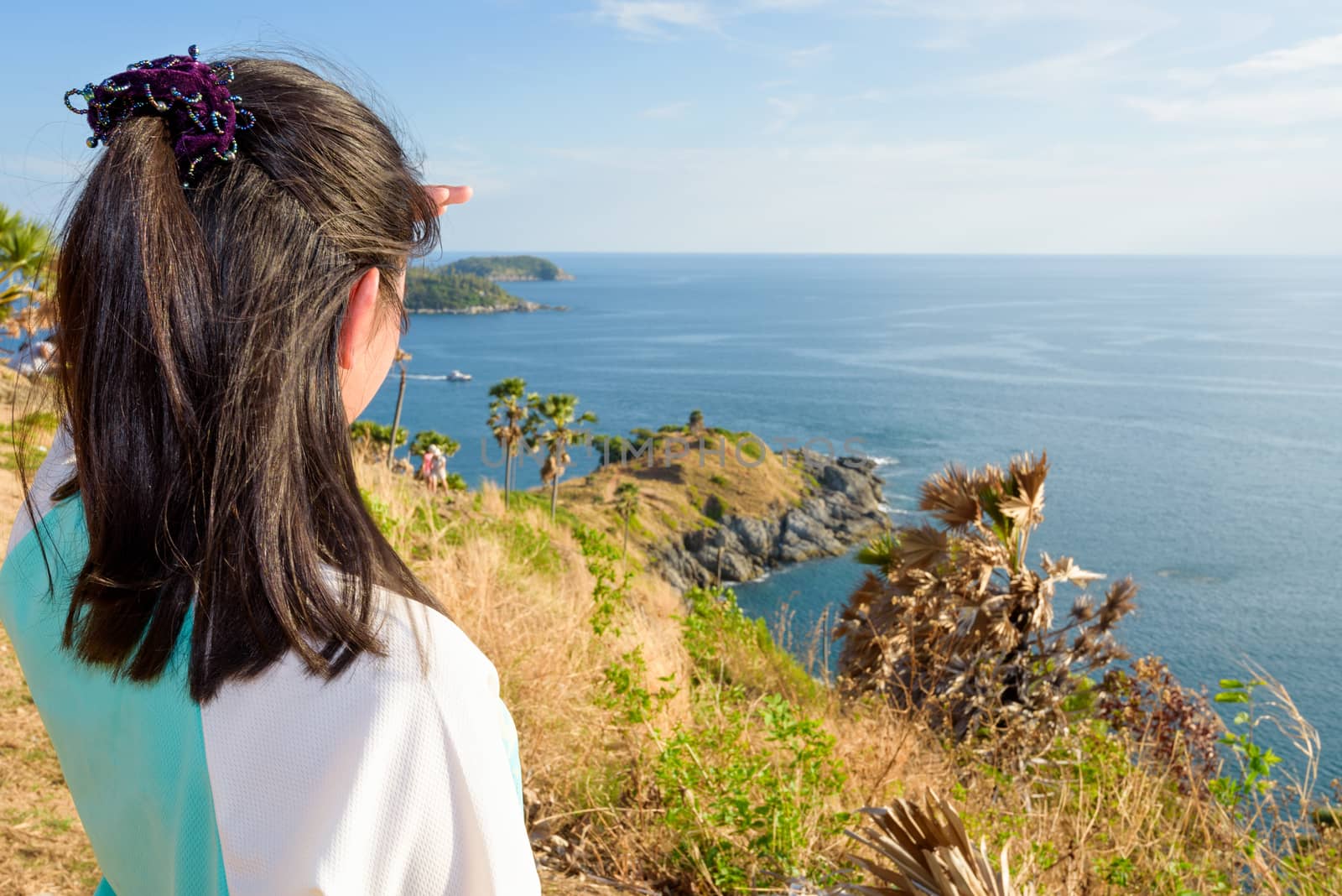 Back of the women tourist looking at beautiful nature sea and island with a happy on the mountain viewpoint at Laem Phromthep Cape a famous attractions of Phuket Province in Thailand