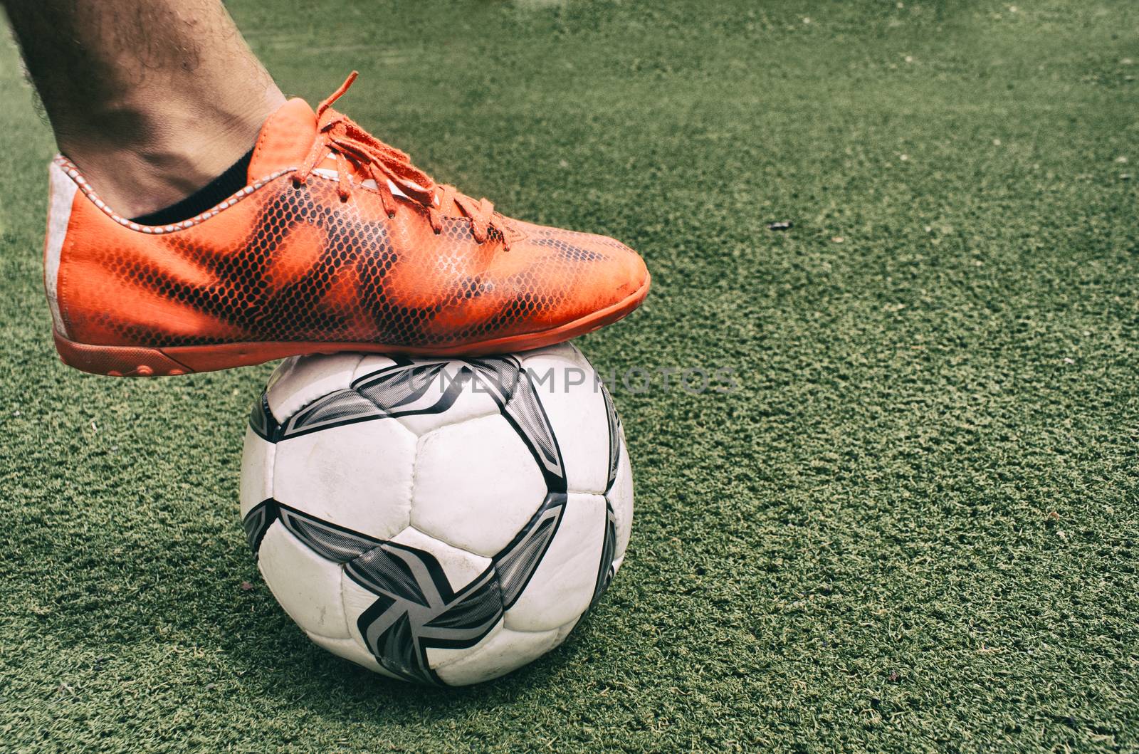 Photograph of a foot and a soccer ball on the grass