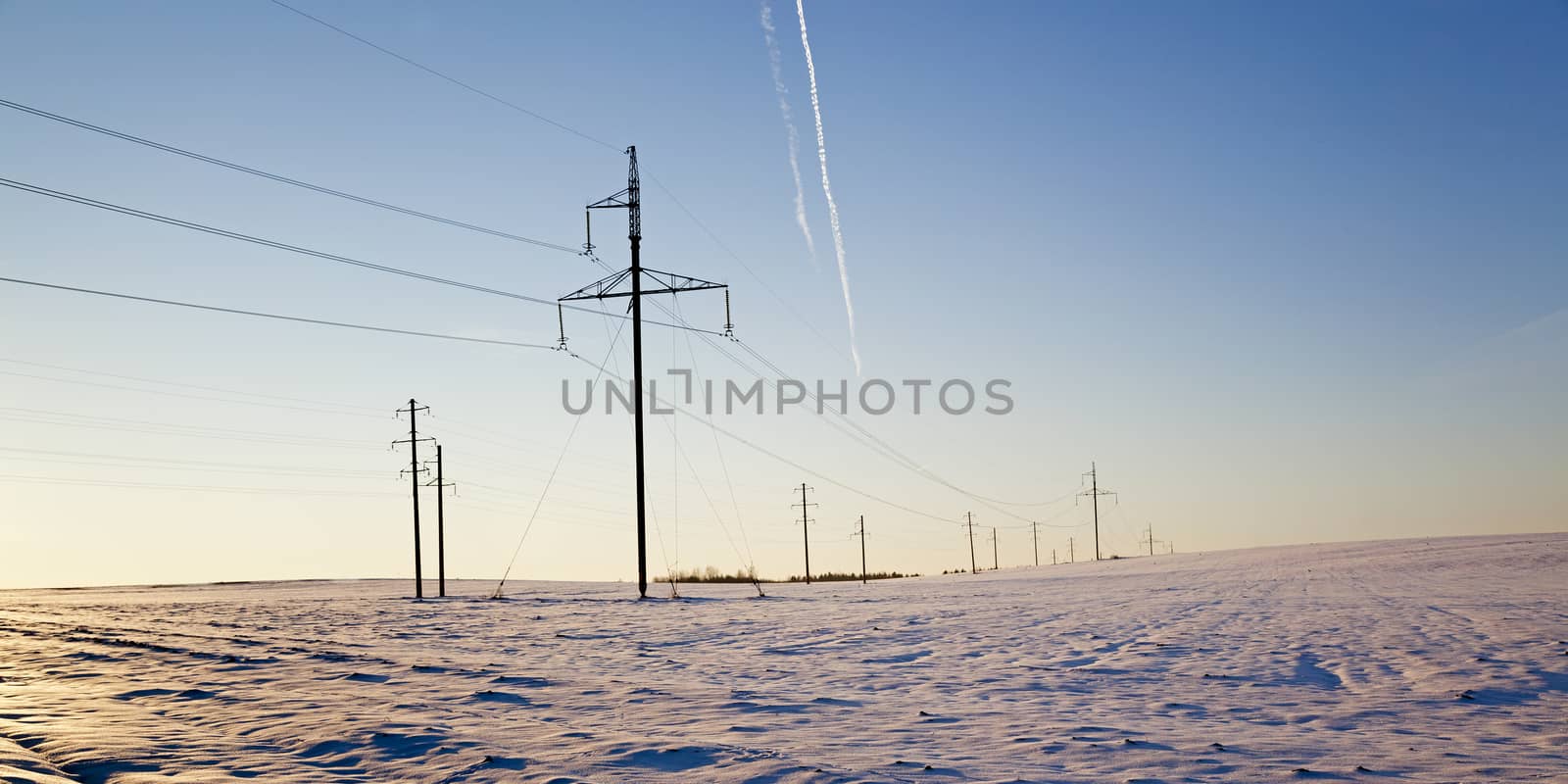  the electric columns which are standing in the field. winter.