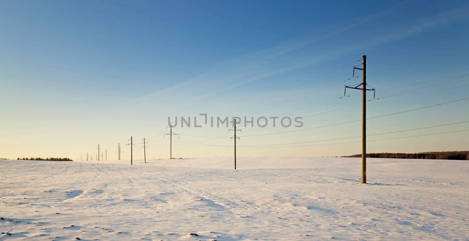  the electric columns which are standing in the field. winter.