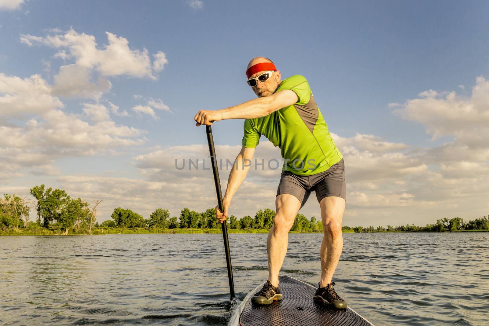 senior muscular male paddler enjoying paddling stand up paddleboard  on a local lake in Fort Collins, Colorado