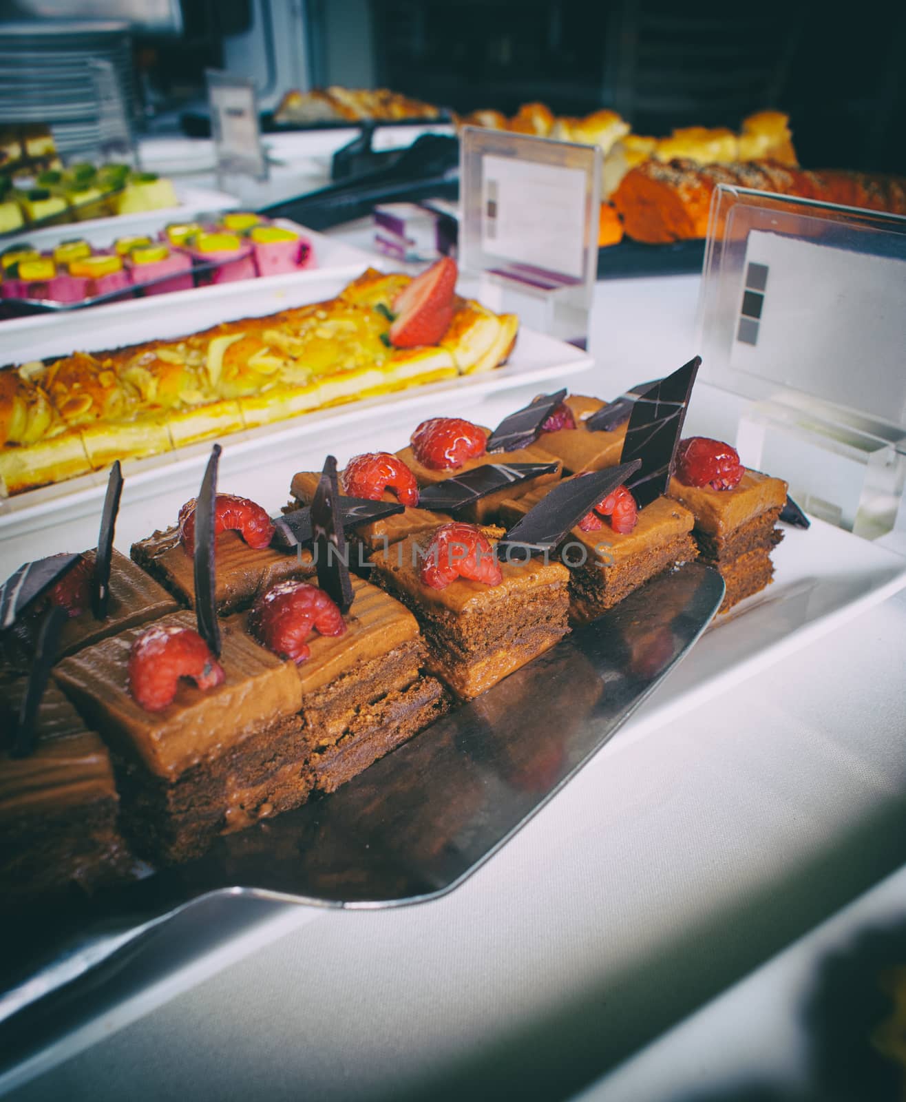 Photograph of a chocolate and strawberry dessert on a table with other fruit desserts