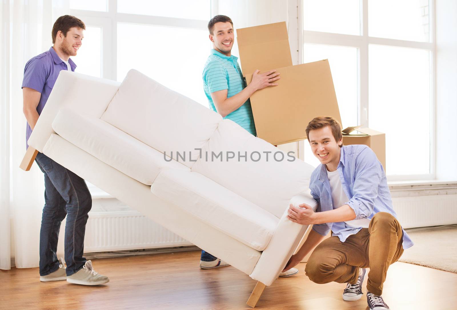 smiling friends with sofa and cardboard boxes by dolgachov