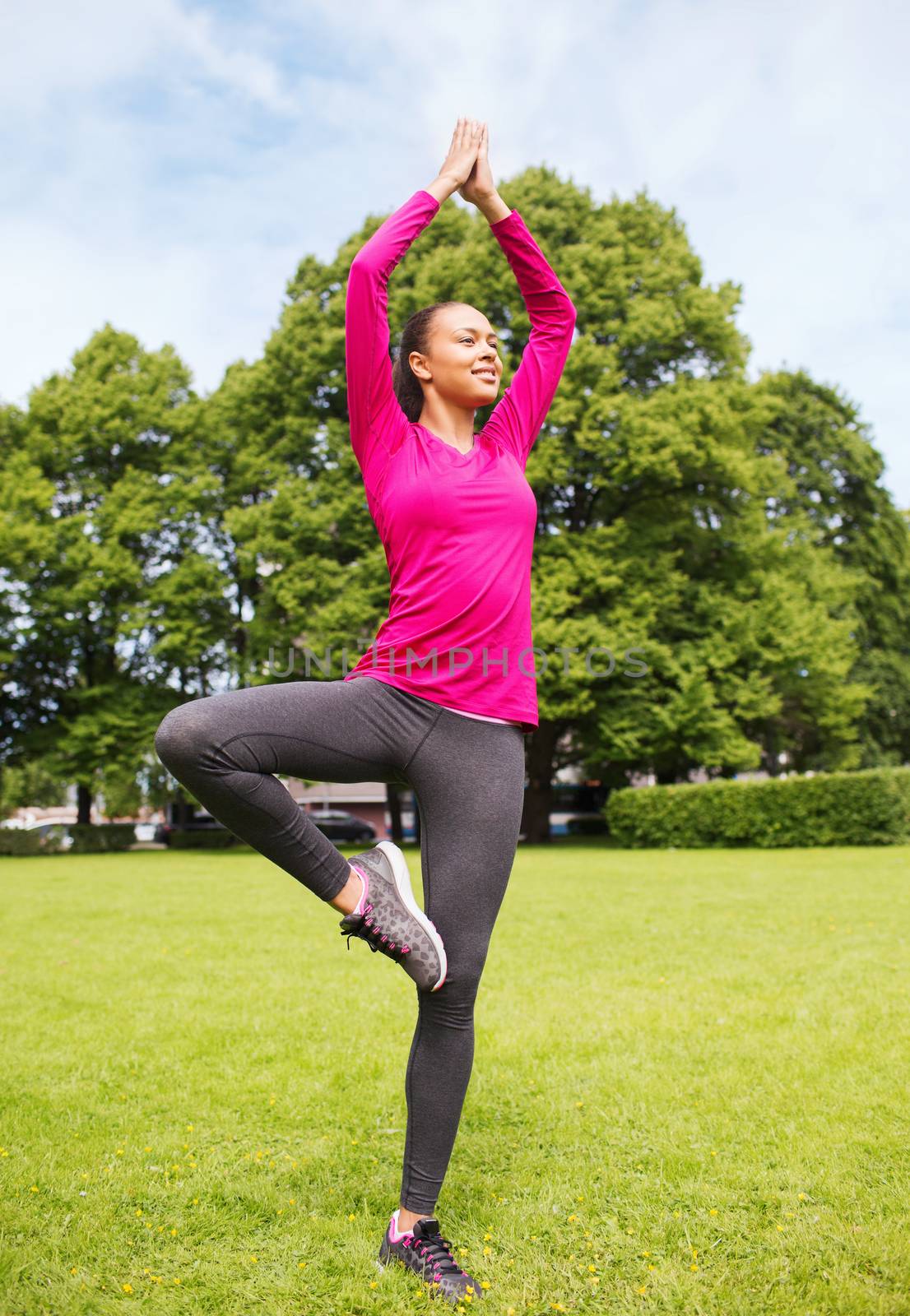 sport, exercise, yoga, park and lifestyle concept - smiling african american woman exercising outdoors