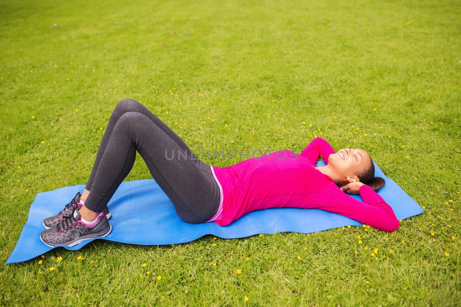 smiling woman doing exercises on mat outdoors by dolgachov