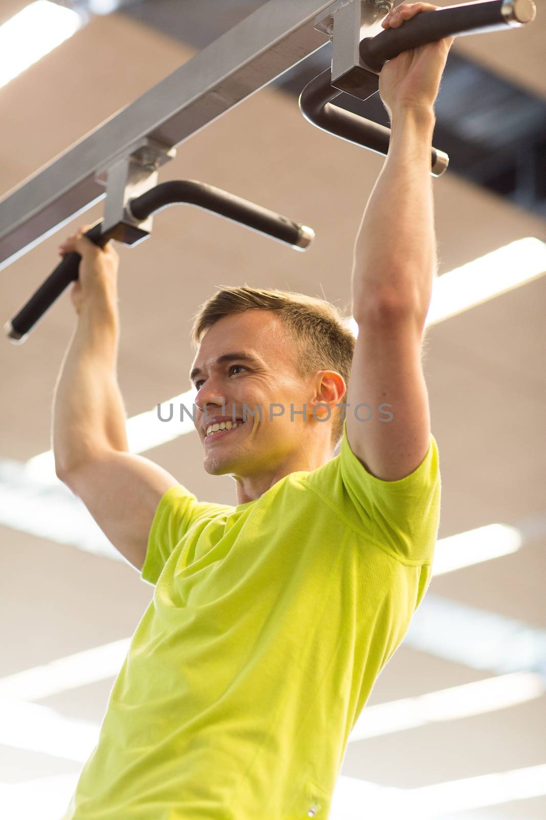 smiling man exercising in gym by dolgachov