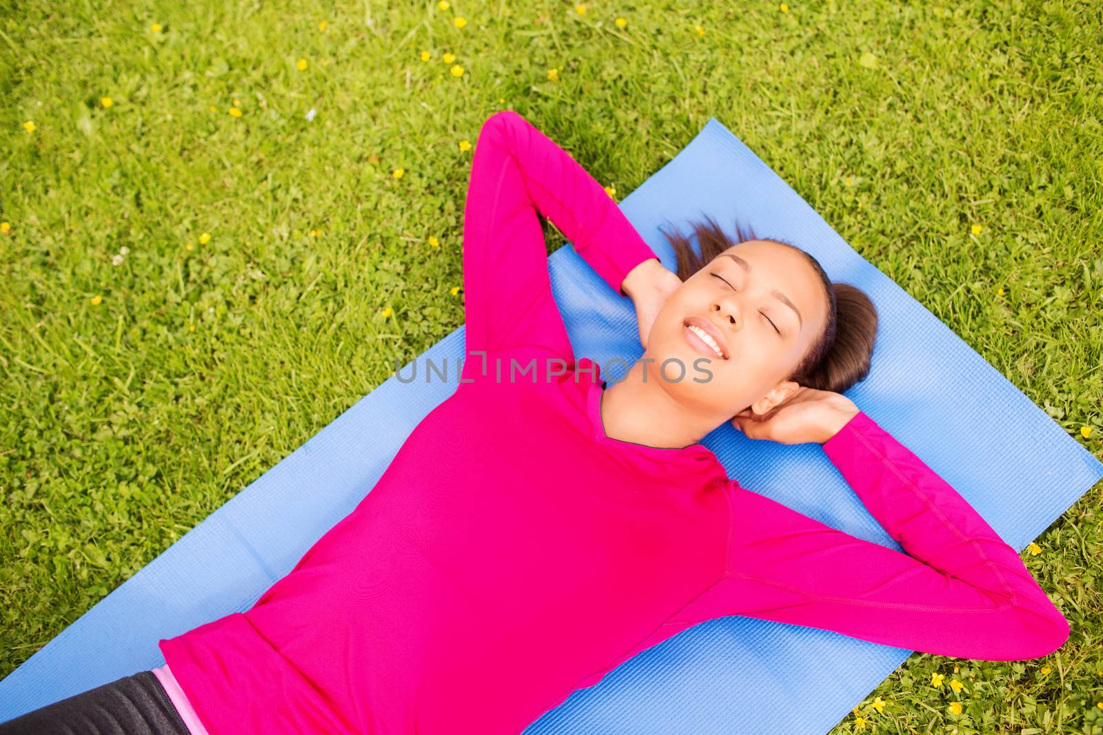 fitness, sport, training, park and lifestyle concept - smiling african american woman doing exercises lying on mat outdoors