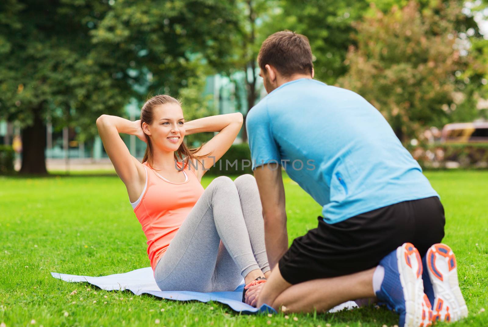 smiling woman doing exercises on mat outdoors by dolgachov