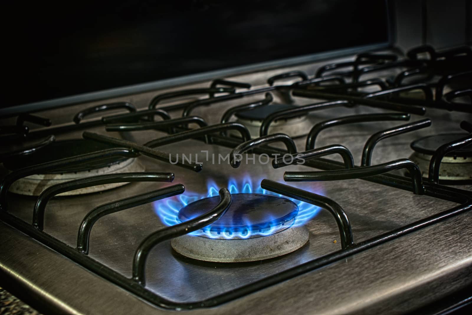 Photograph of a lighted metal gas stove and blue fire flame