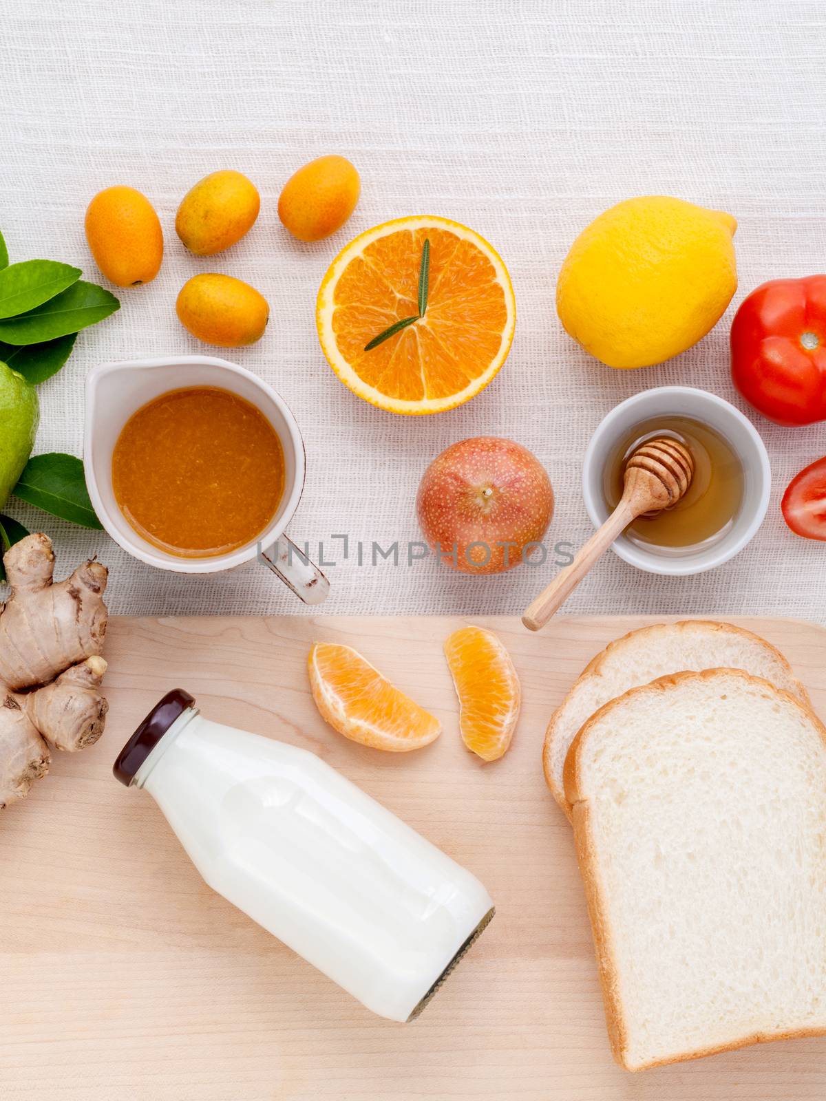 Breakfast with orange juice, oranges, oranges slice, passion fruit , ginger,tomato and Kiwi set up on wooden table .