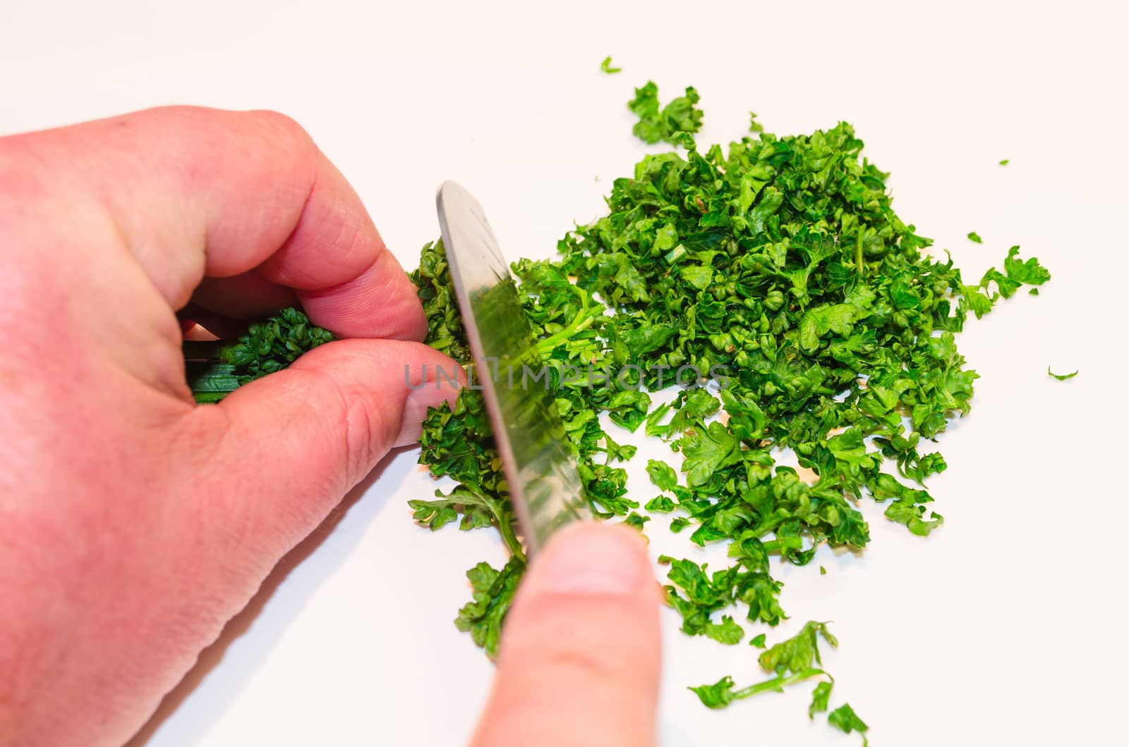 Chopping parsley with a knife on a cutting board.