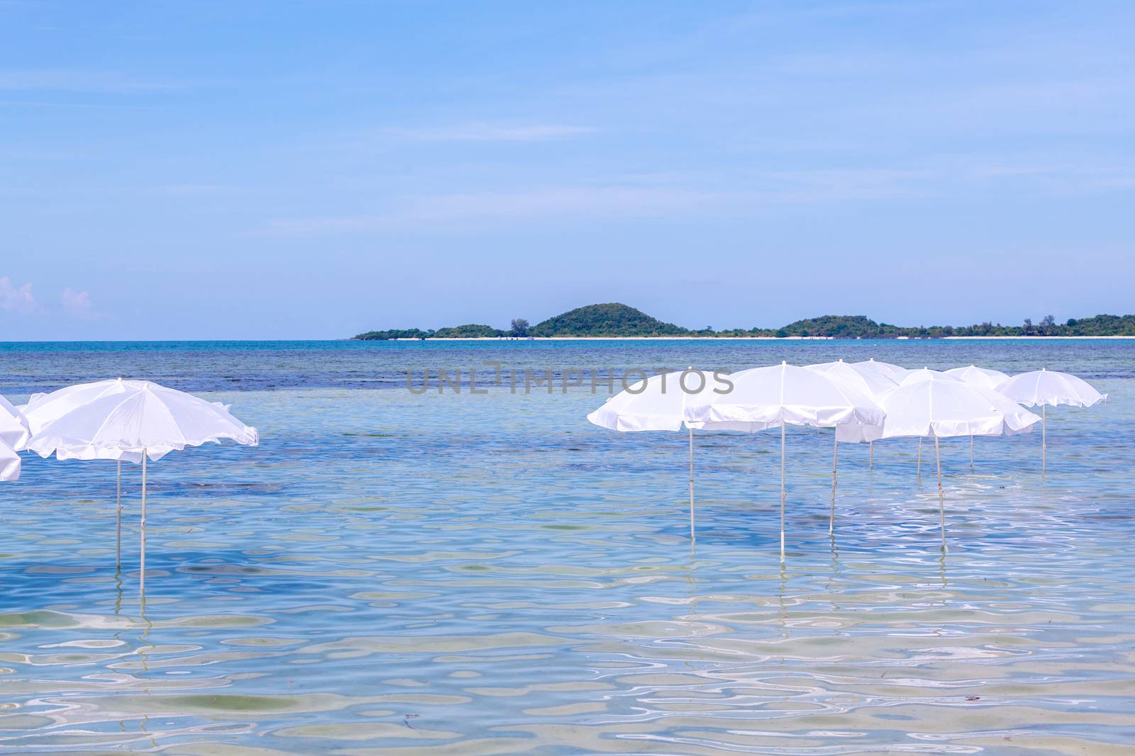 White umbrella on summer tropical beach with sailing boat.