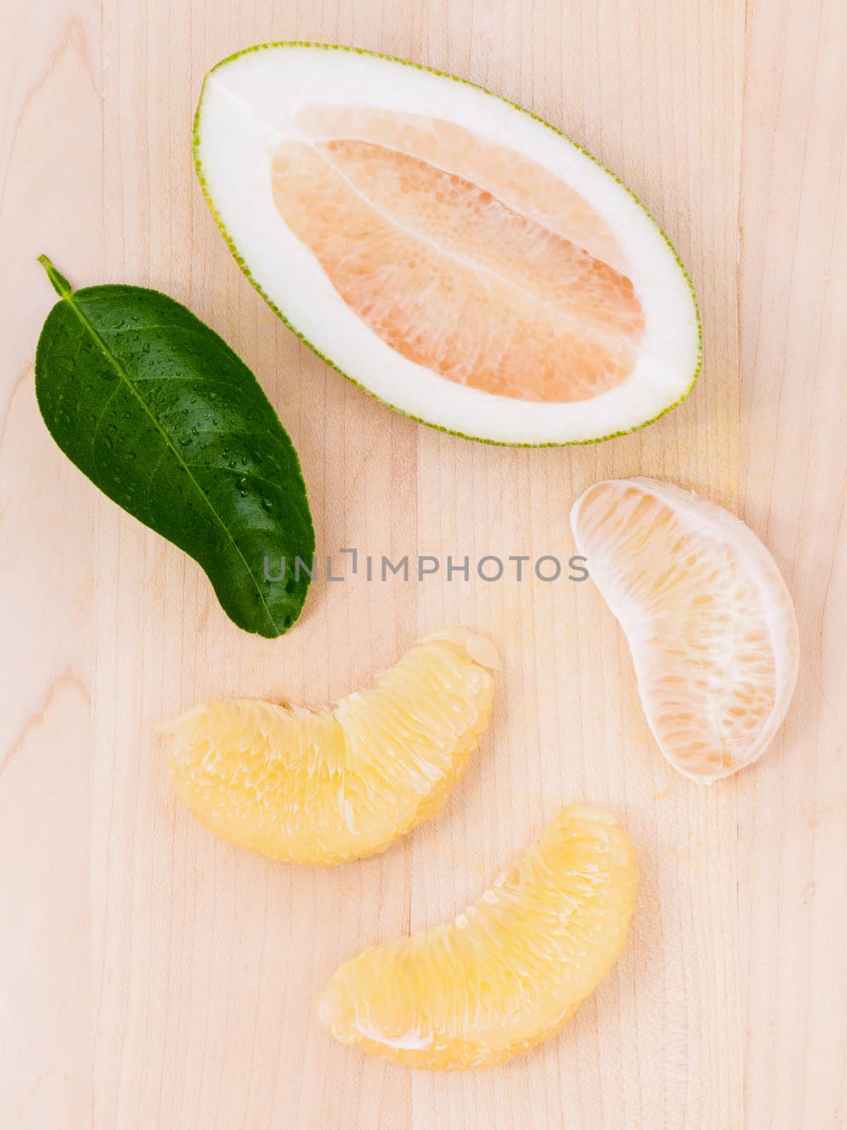 Fresh pomelo cutting and peeled on the wooden background.